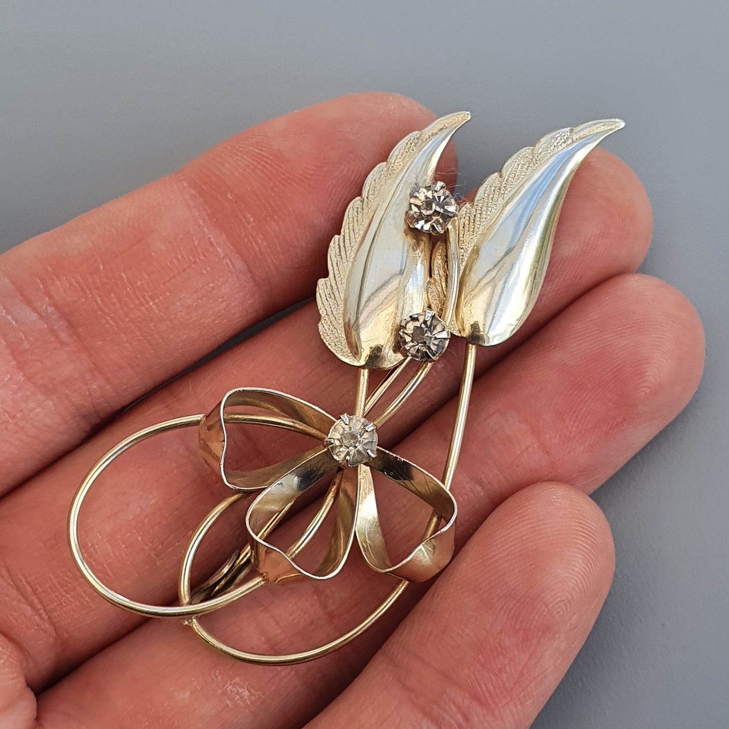 Delicate gold brooch featuring leaf-like shapes and small gemstones.