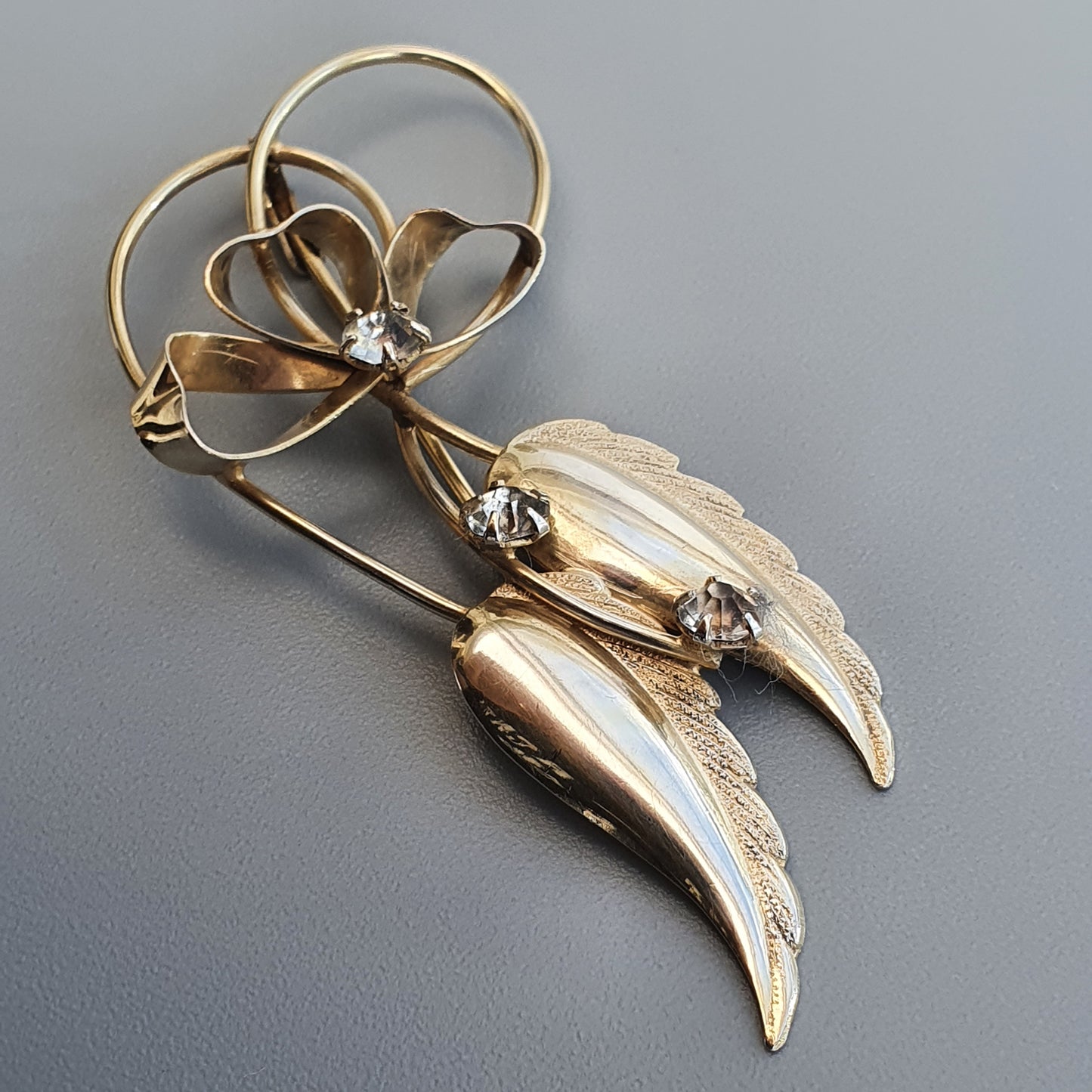 Gold-toned floral brooch with leaf-like shapes and small gemstones.