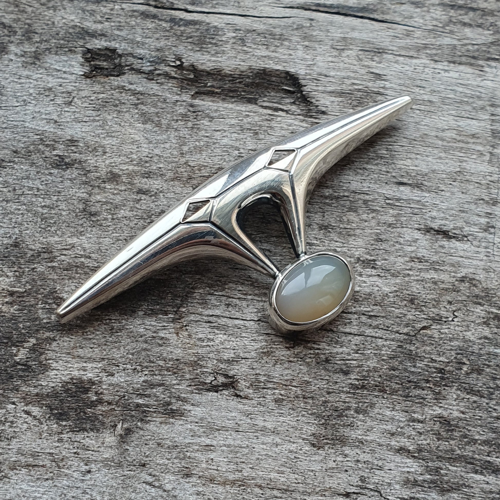 Silver pendant with an elongated star-like shape and a central opal stone.