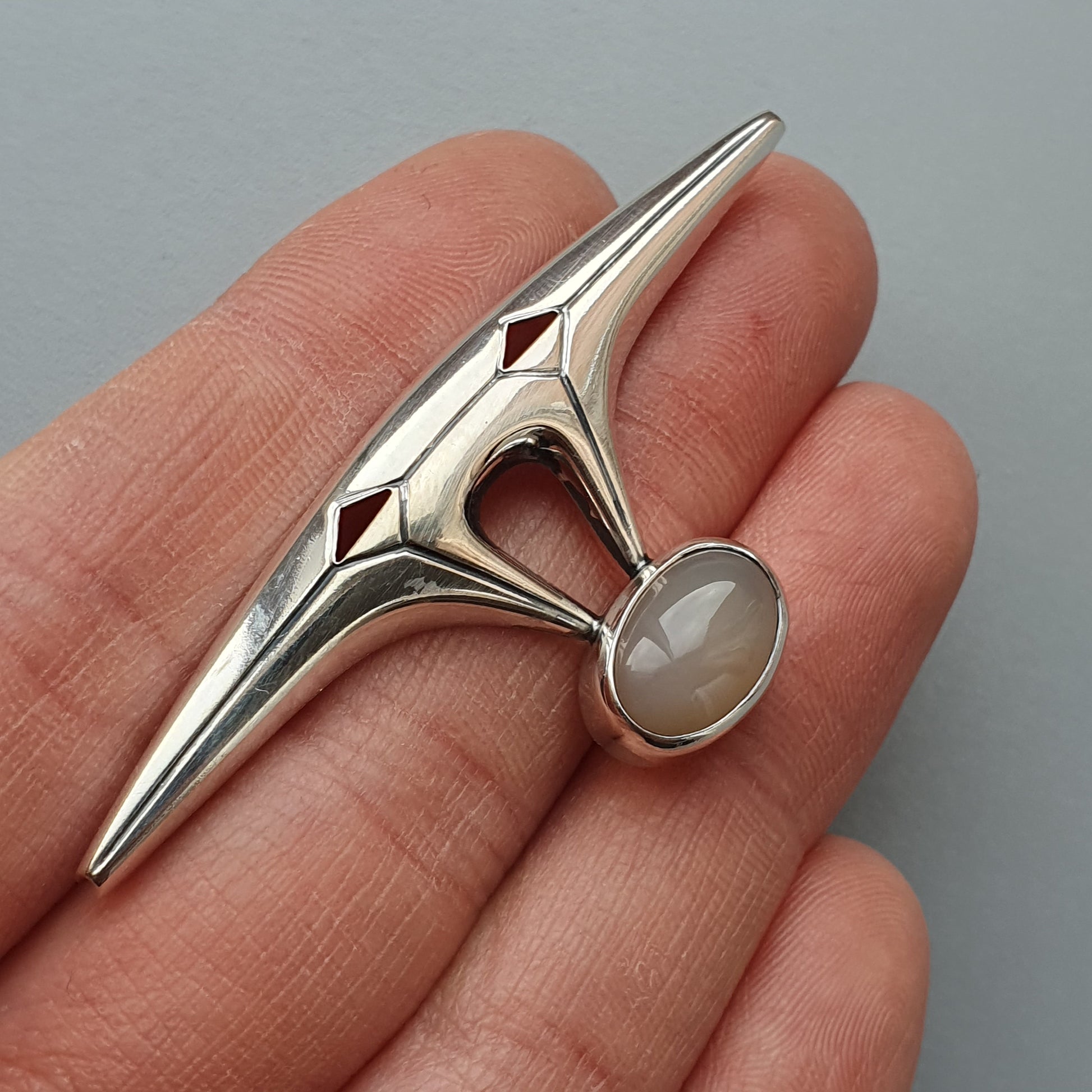 Sleek silver ring with a pointed design and a round gemstone.