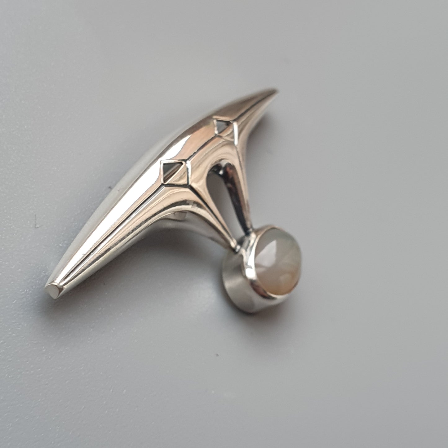 Sleek, futuristic-looking silver ring with a pointed top and a spherical element at its base.