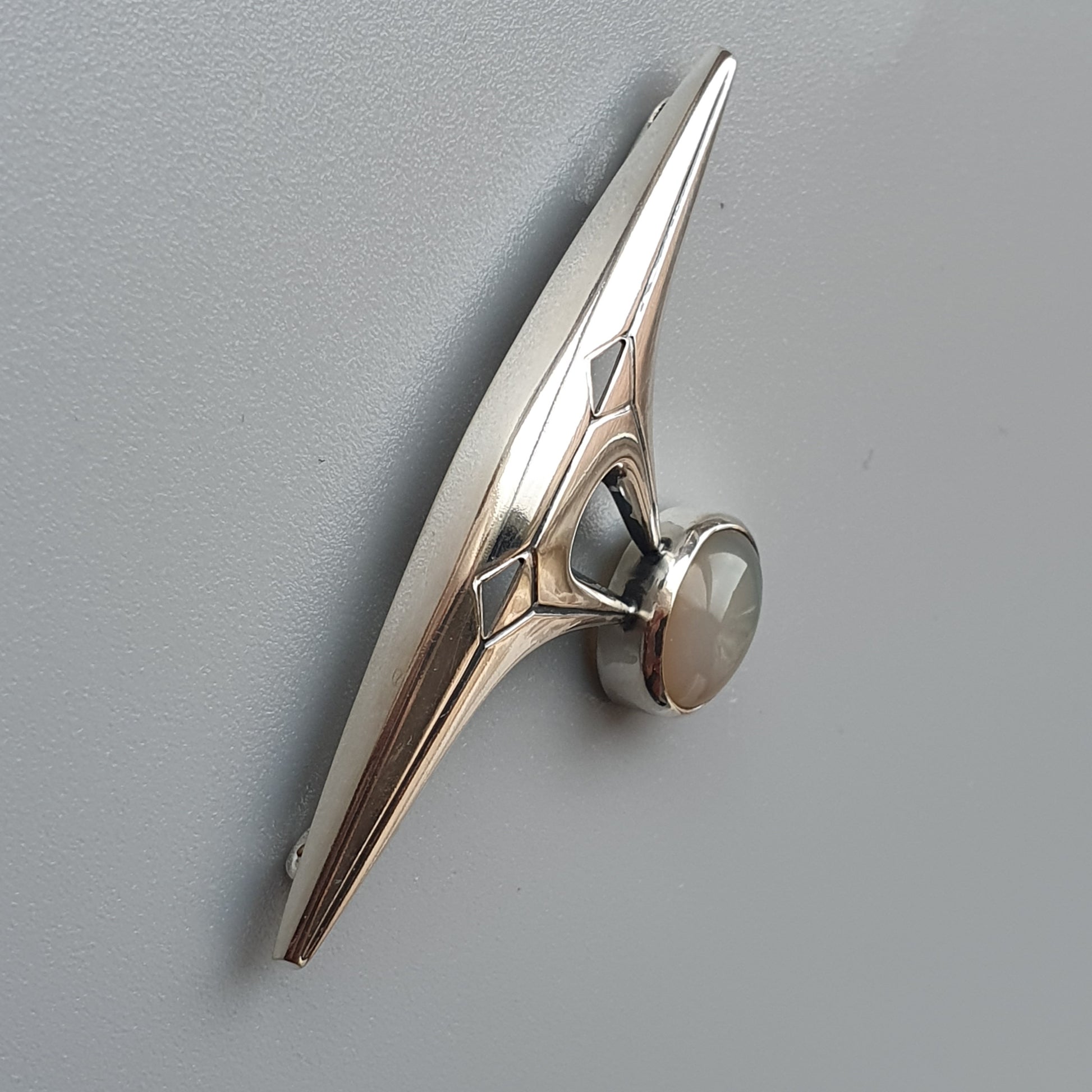 Metallic silver binder clip or paper clip with a sleek, elongated design.