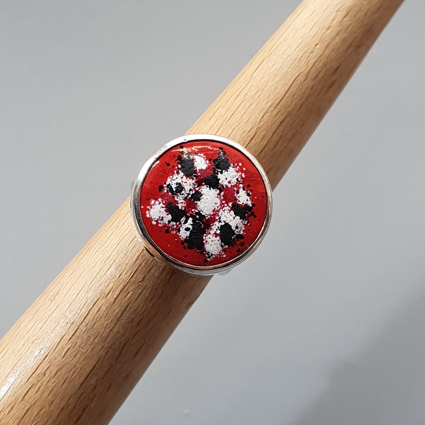 Colorful beaded ring with a red background set in a round metal frame.