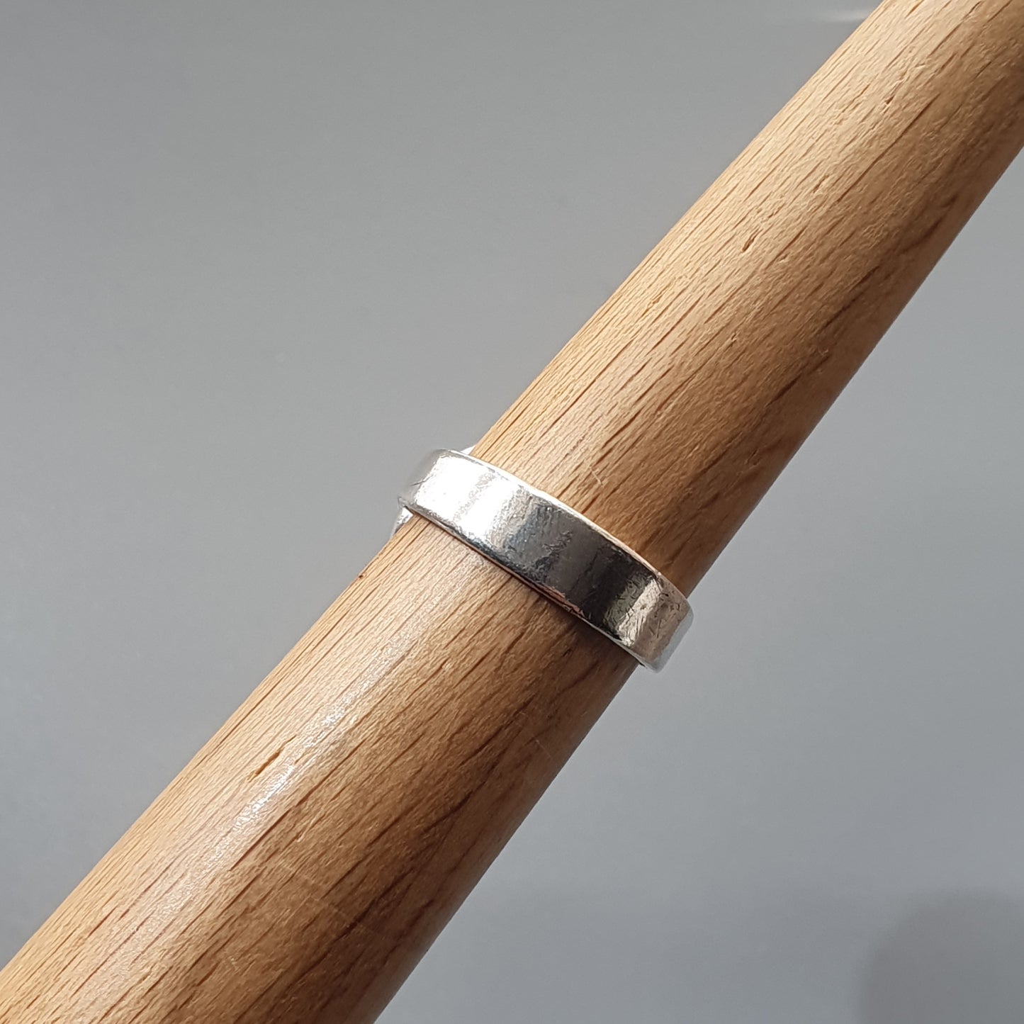 Silver ring encircling a wooden dowel or rod.