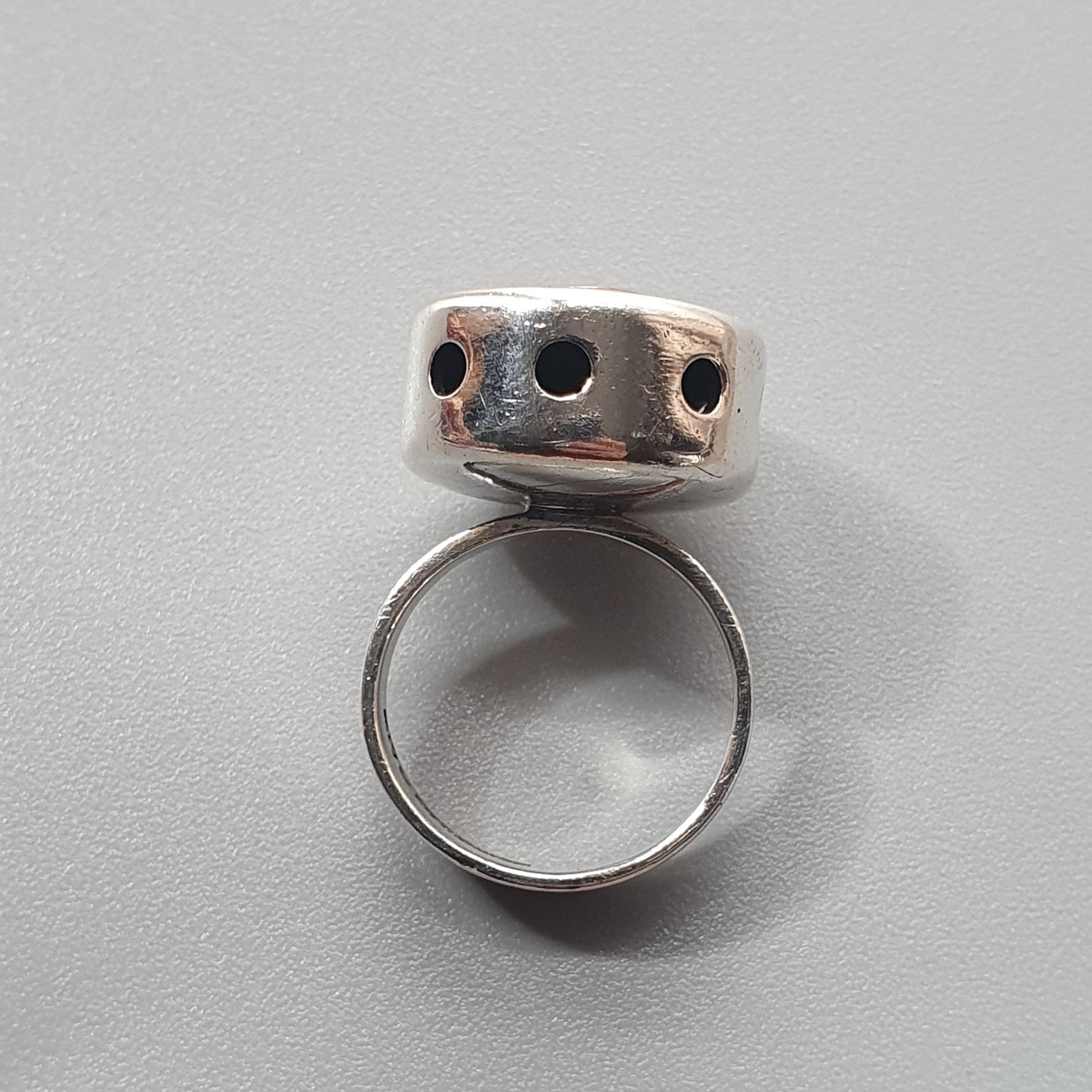 Silver ring with a cylindrical top featuring three small holes.