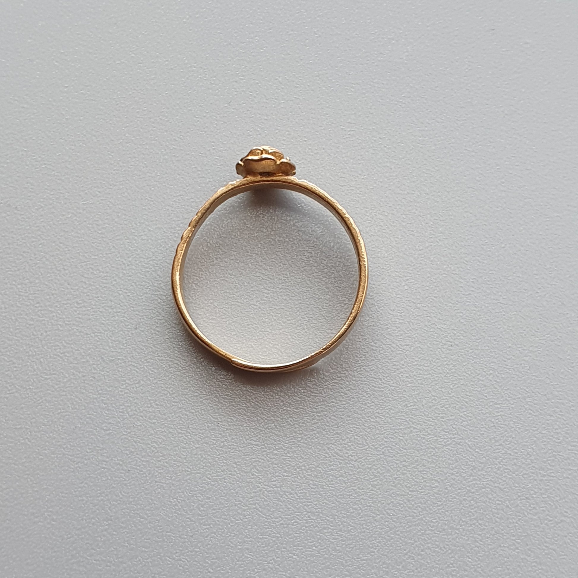 Gold ring with a small round gemstone or crystal set in the center.