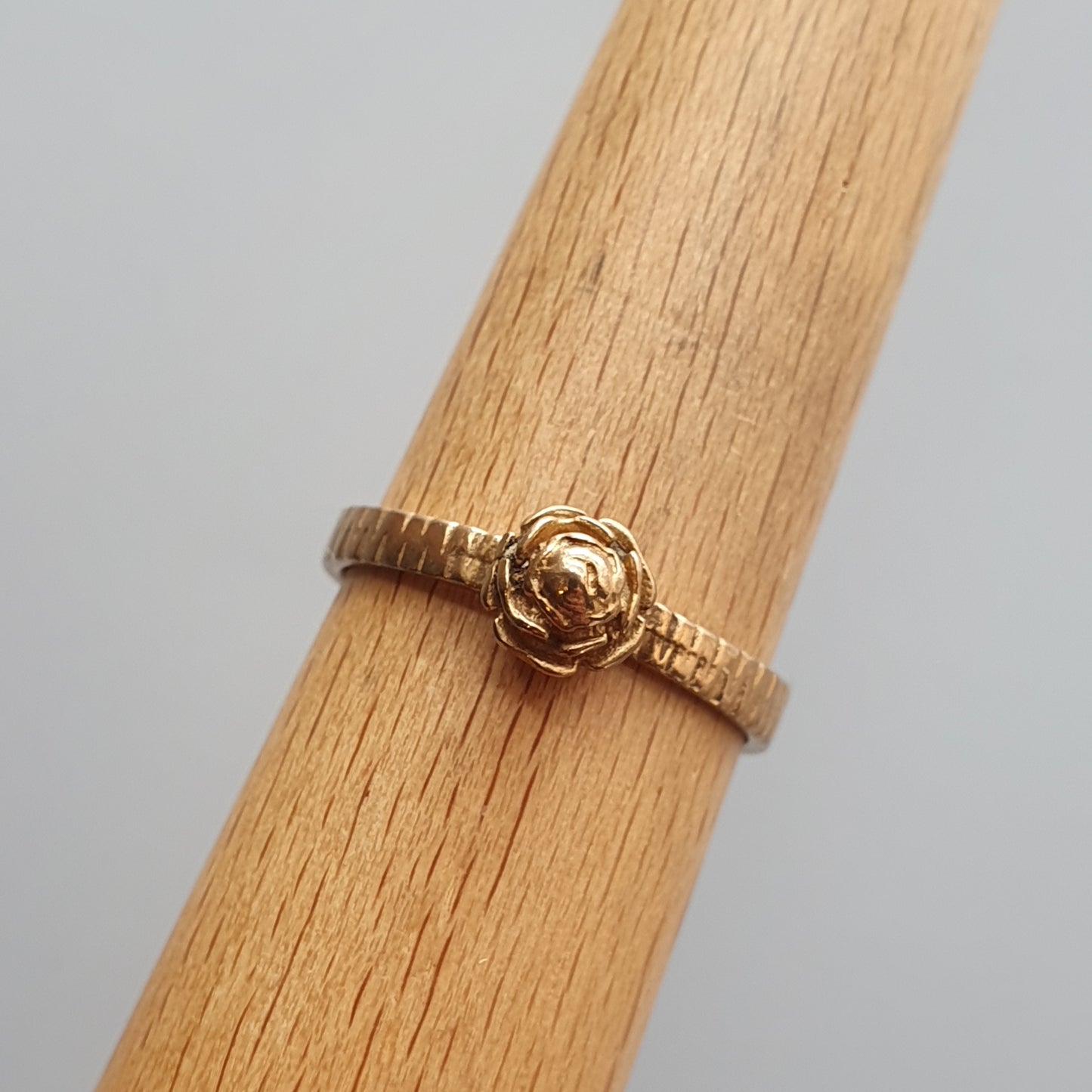 Gold ring with a rose-shaped design on top.