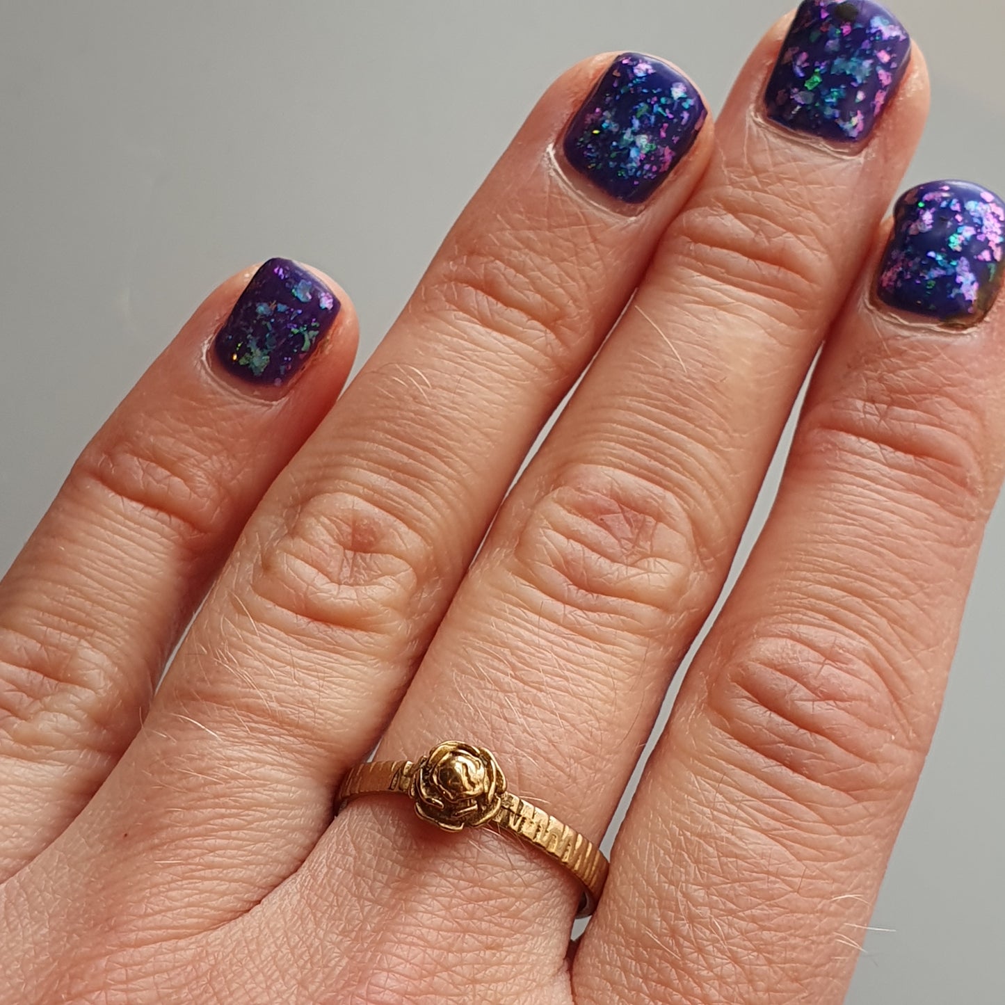 Hand with galaxy-inspired nail polish and a gold ring.