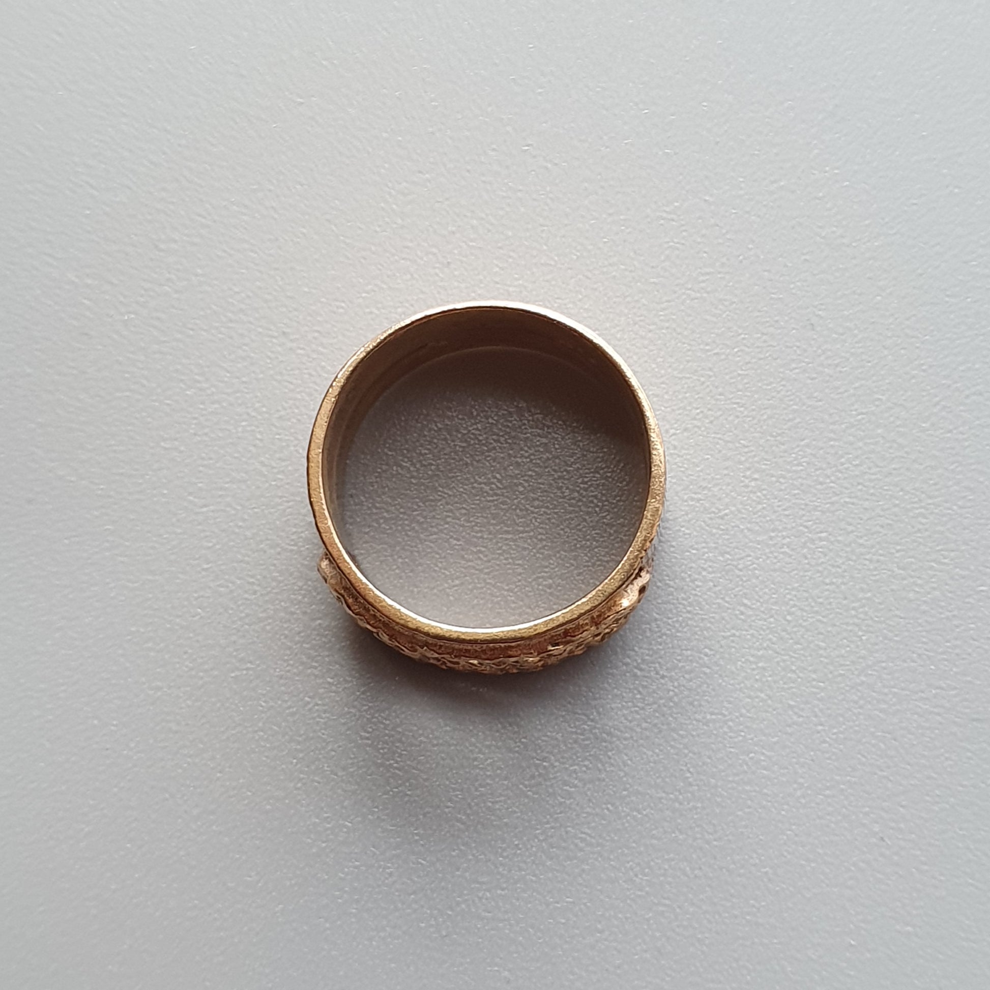 Gold ring with an engraved or textured pattern on its outer surface.