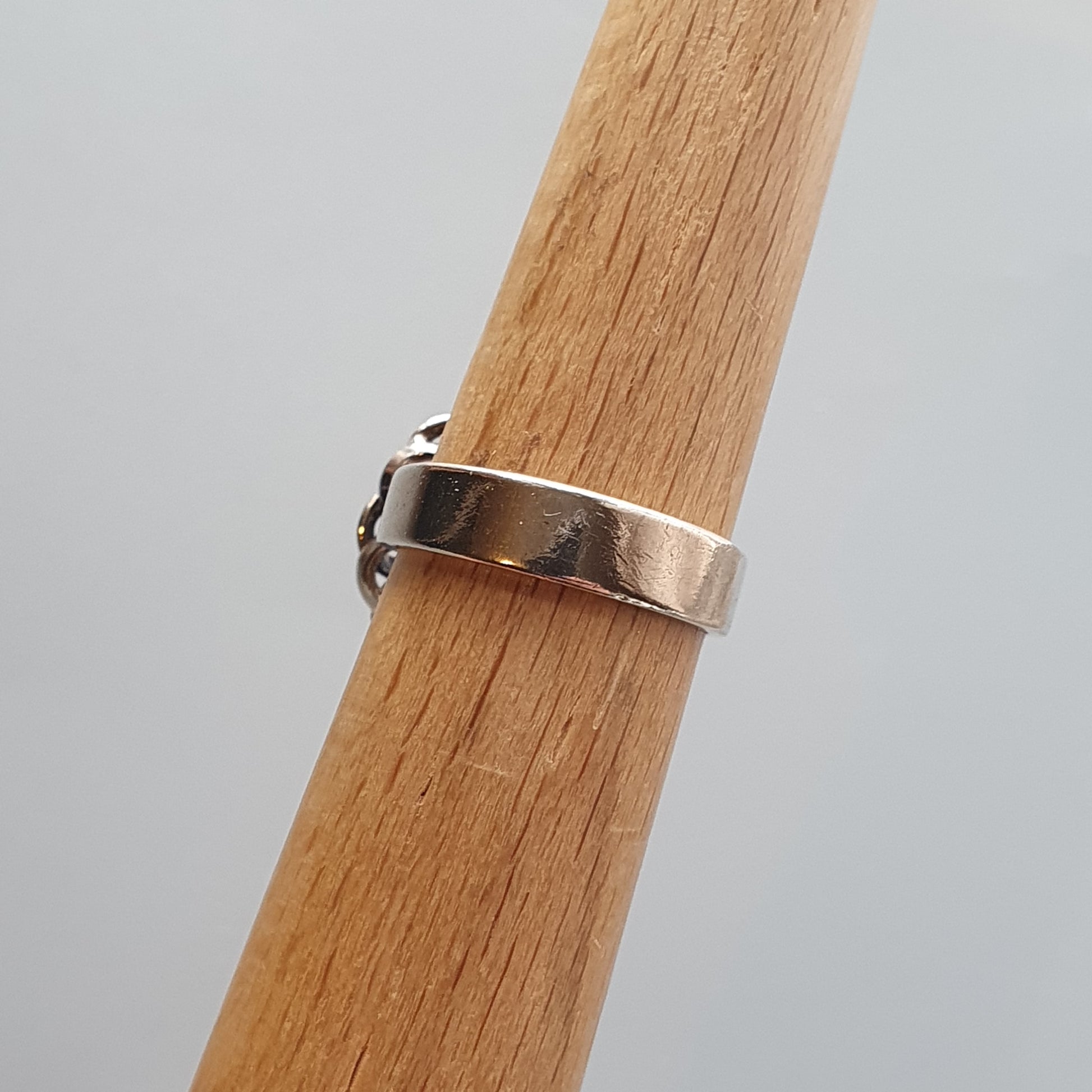 Silver ring with a simple band design worn on a wooden surface.