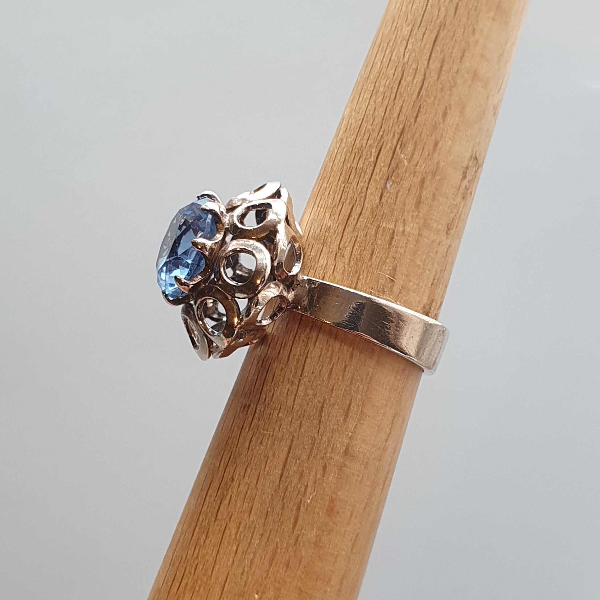 Silver ring with an ornate setting featuring a blue gemstone.