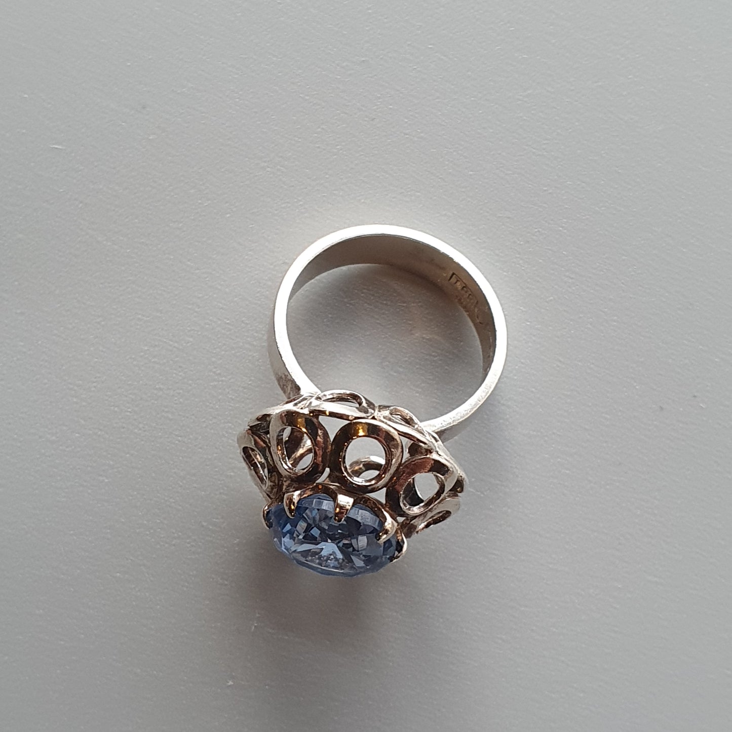 Ornate silver ring with a prominent blue gemstone set in an intricate metalwork design.