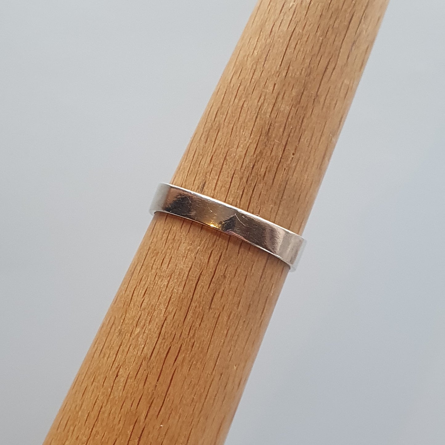 Silver ring wrapped around a wooden cylinder or dowel.