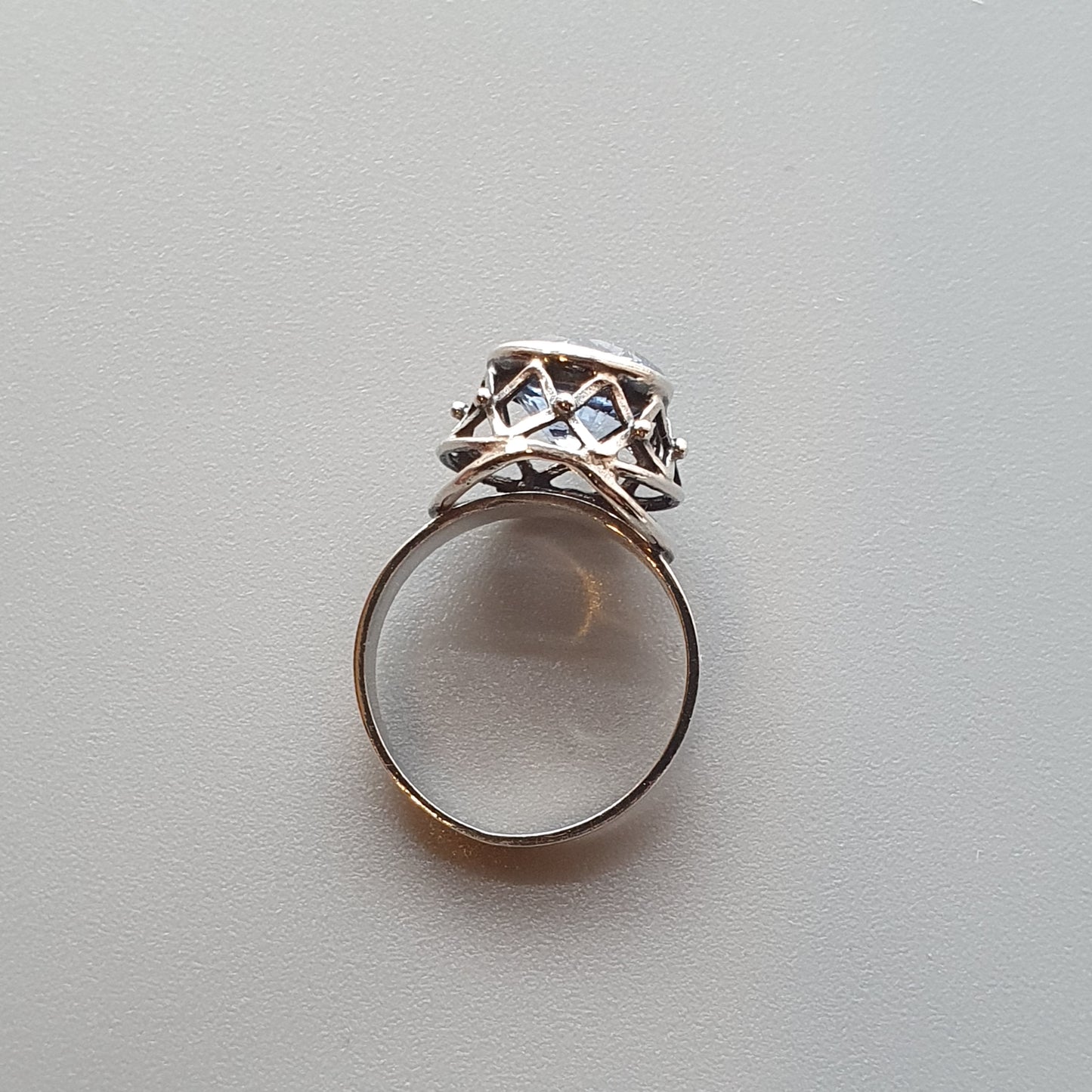 Silver ring with an intricate openwork design on its crown.