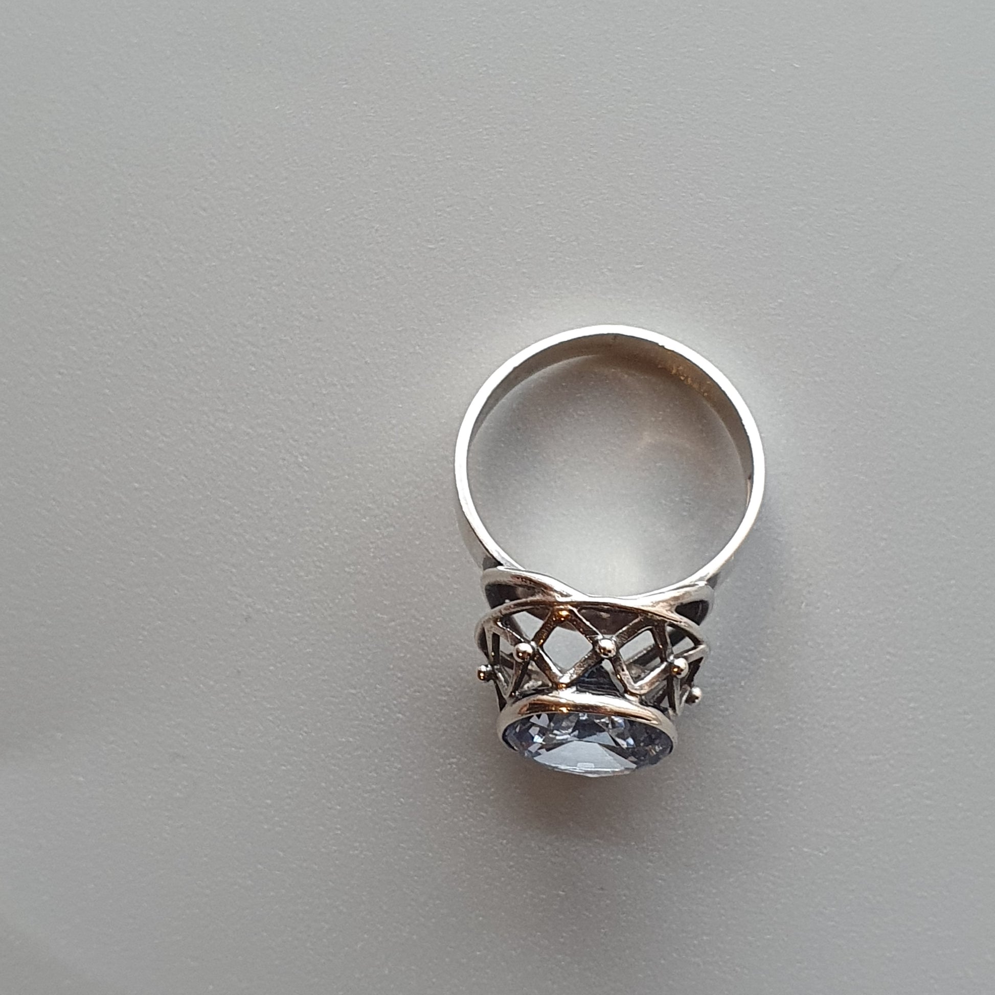 Silver ring with an ornate design and a prominent gemstone setting.