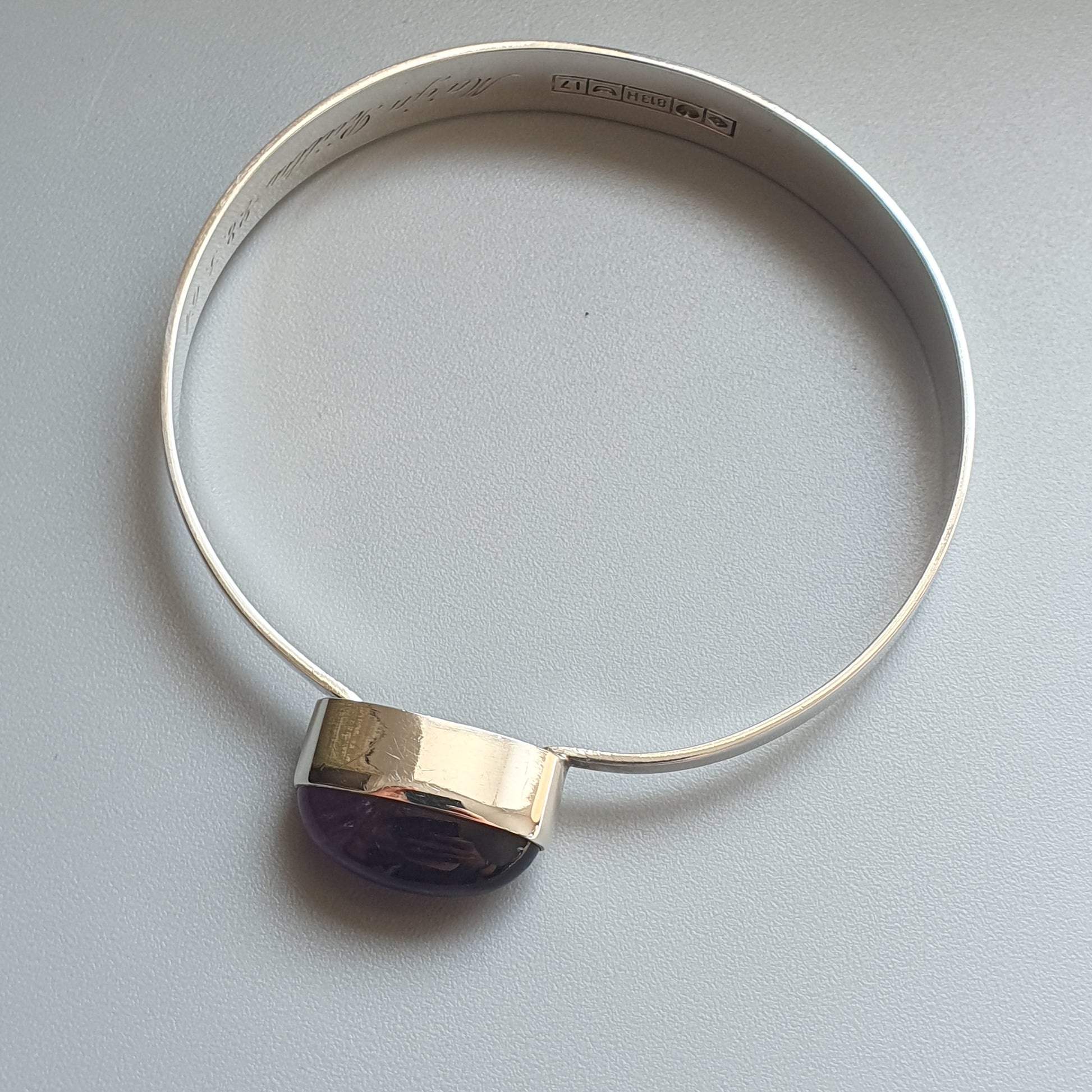 Silver bangle bracelet with a square gemstone or crystal accent.