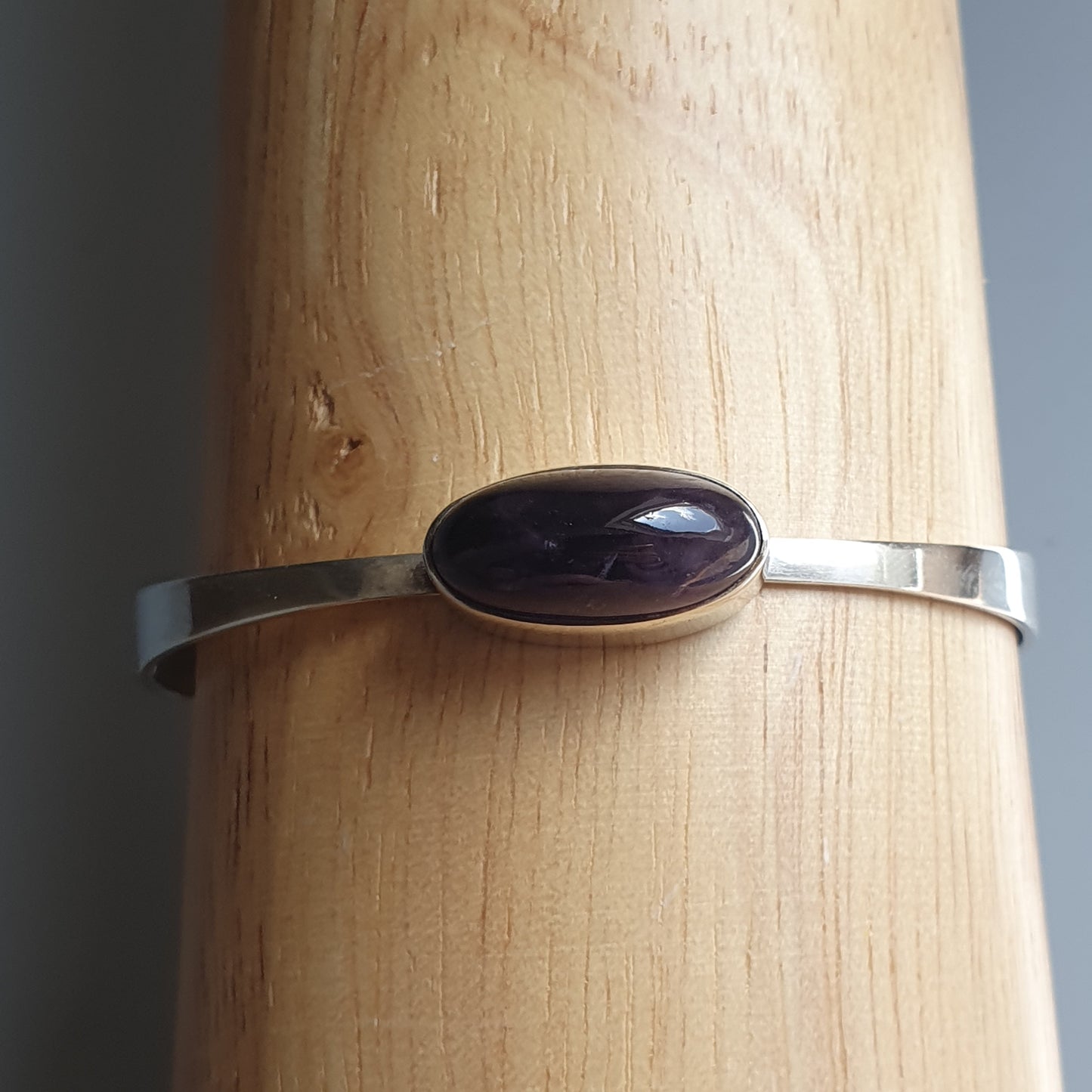 Silver bracelet with an oval purple gemstone.