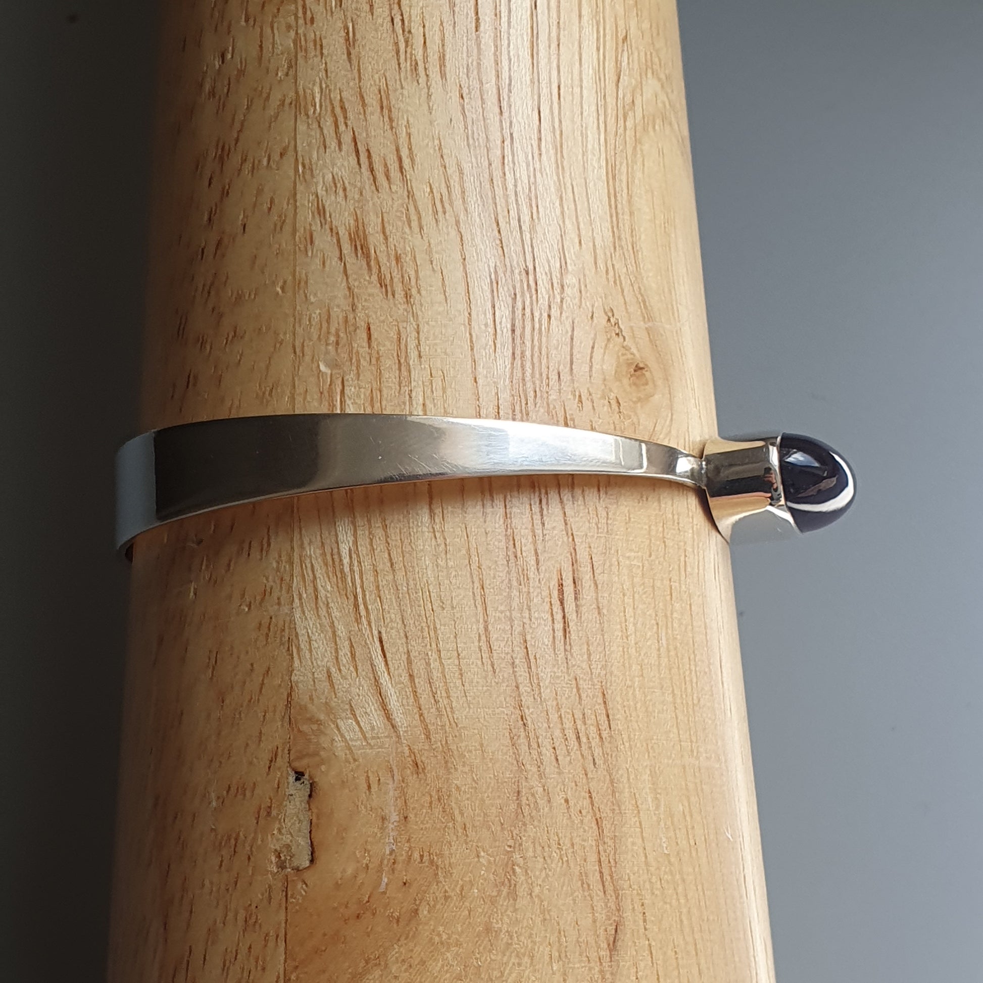 Silver metal bracelet or bangle with a hook clasp.