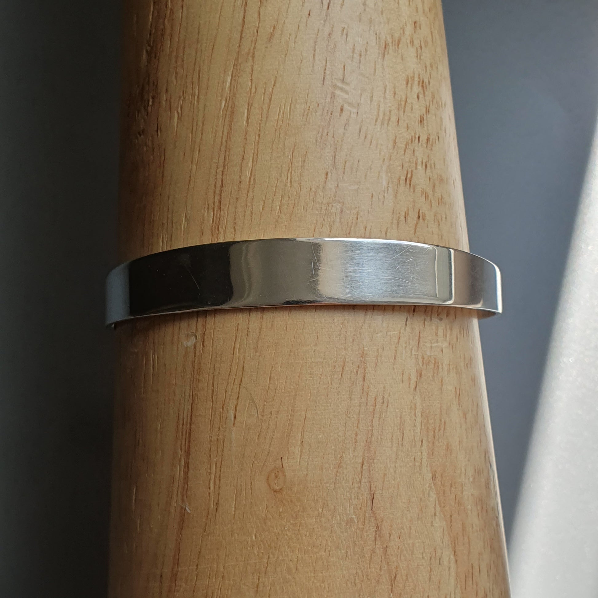 Silver metal ring or band wrapped around a wooden surface.