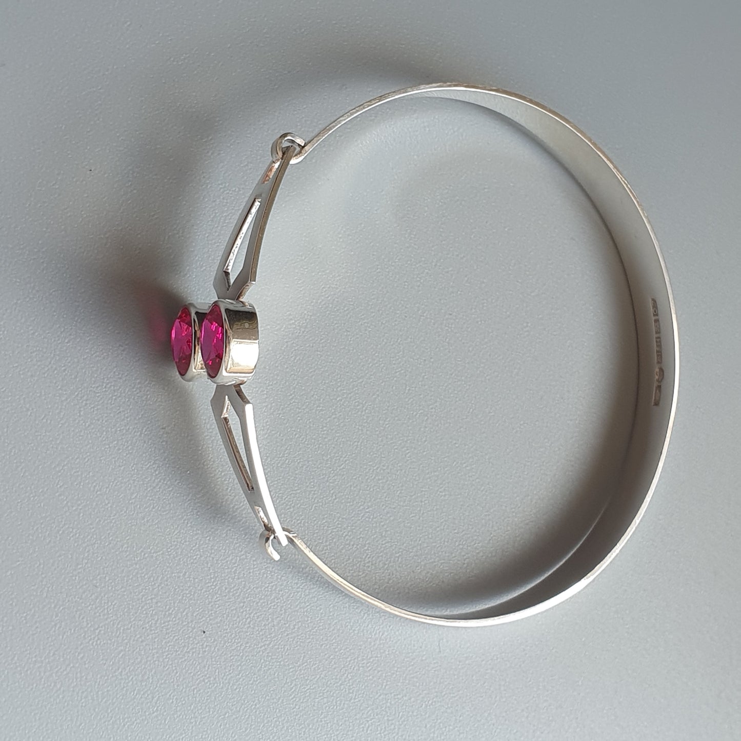 Silver bracelet with two small pink gemstones.