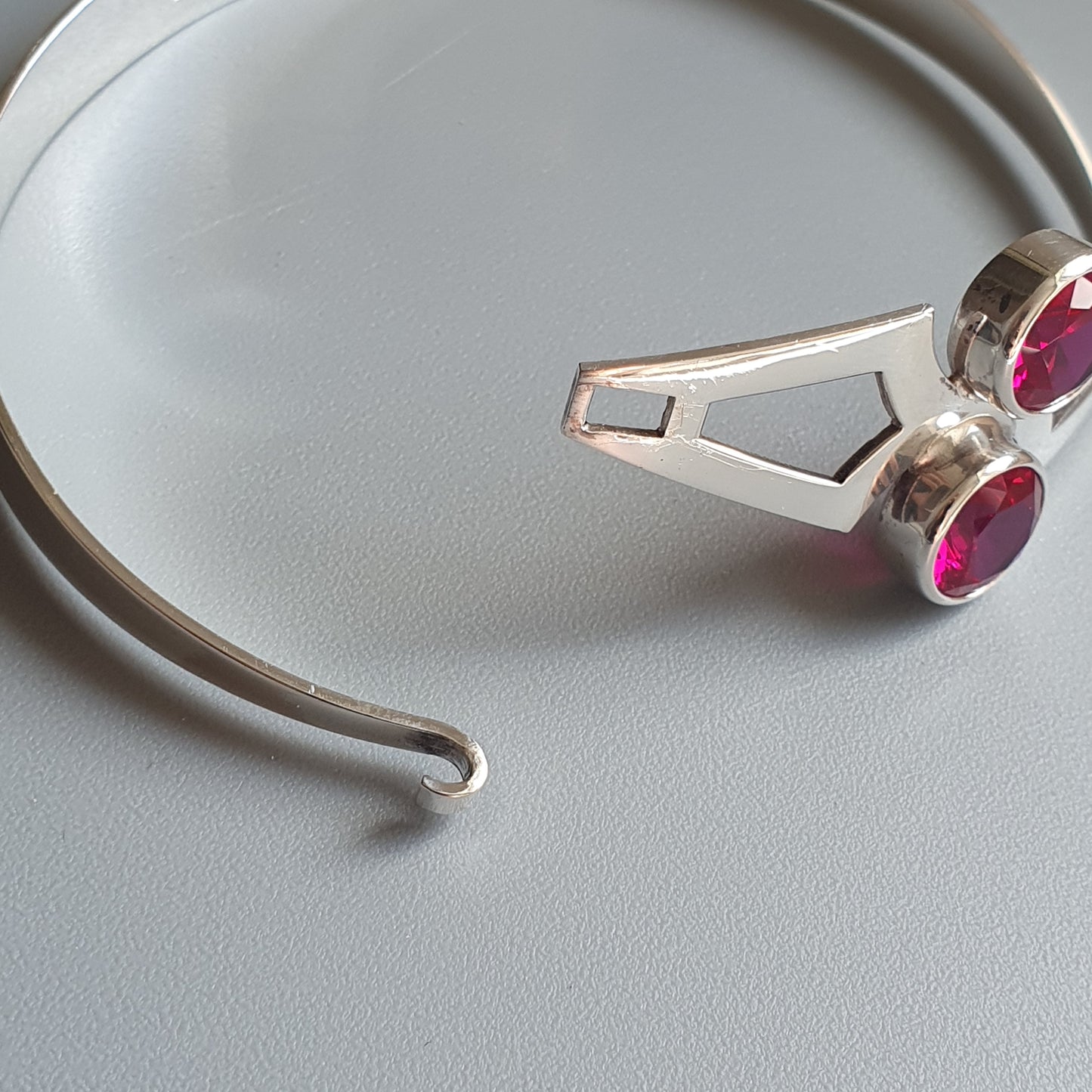 Silver bracelet or bangle with pink gemstone accents.