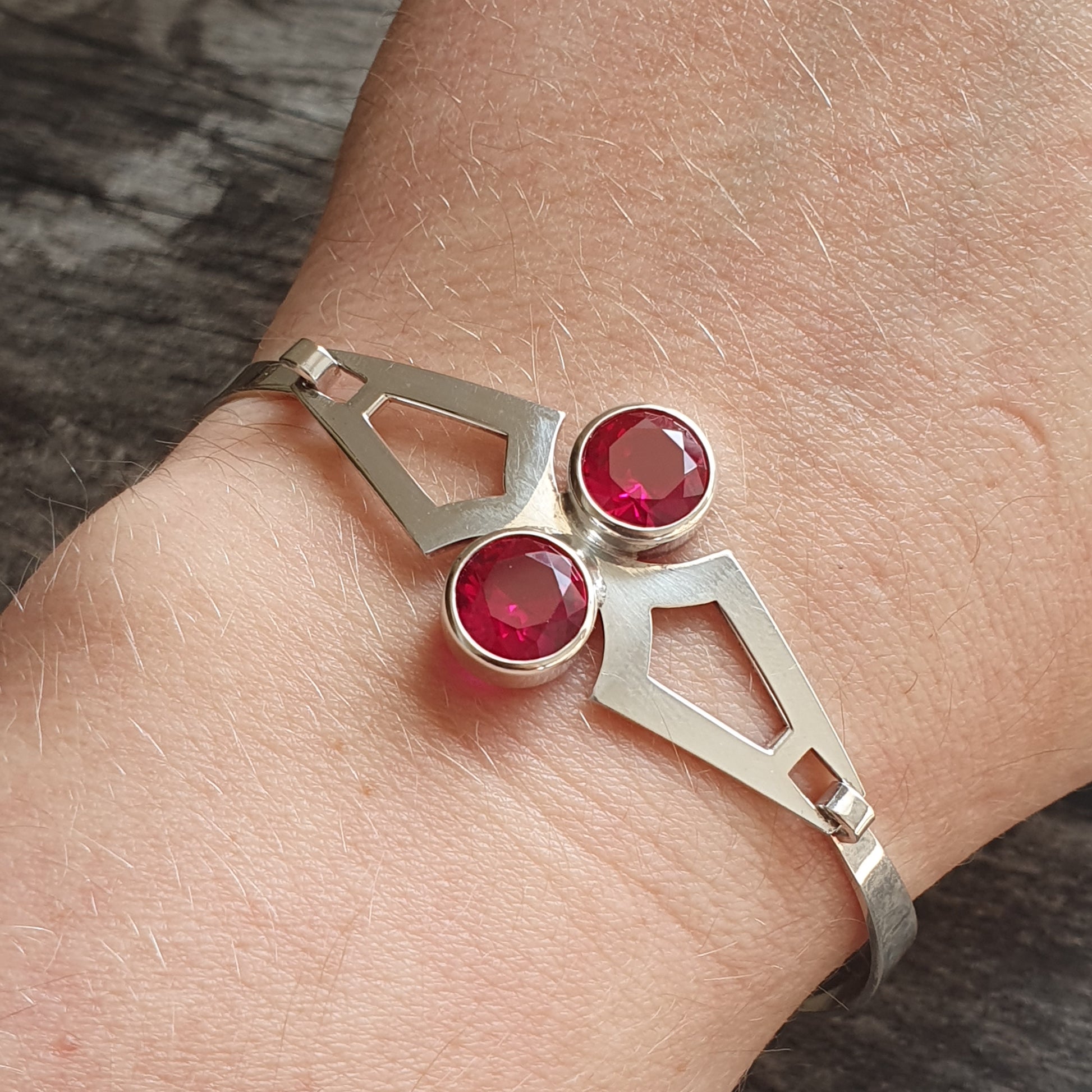 Silver bracelet with two red gemstones set in a geometric design.