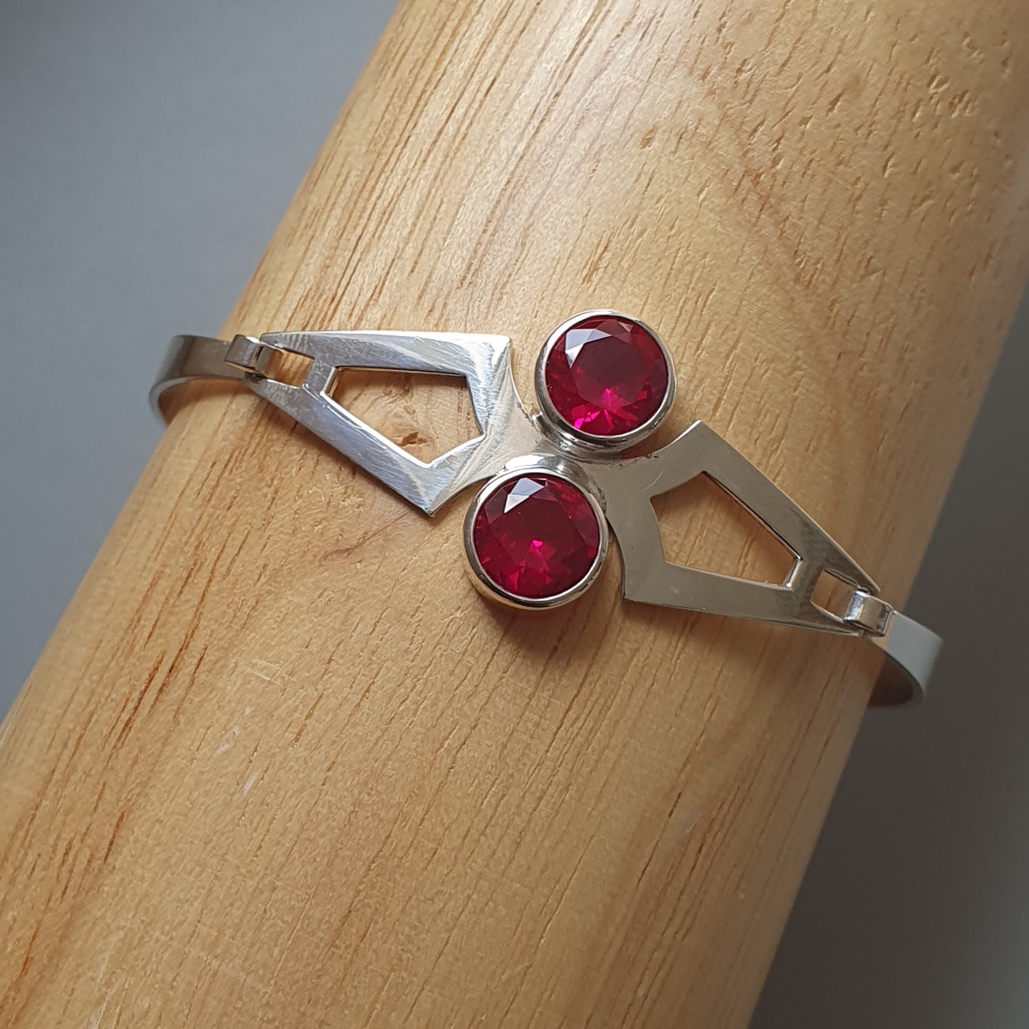 Silver ring with two small red gemstones set in an angular design.