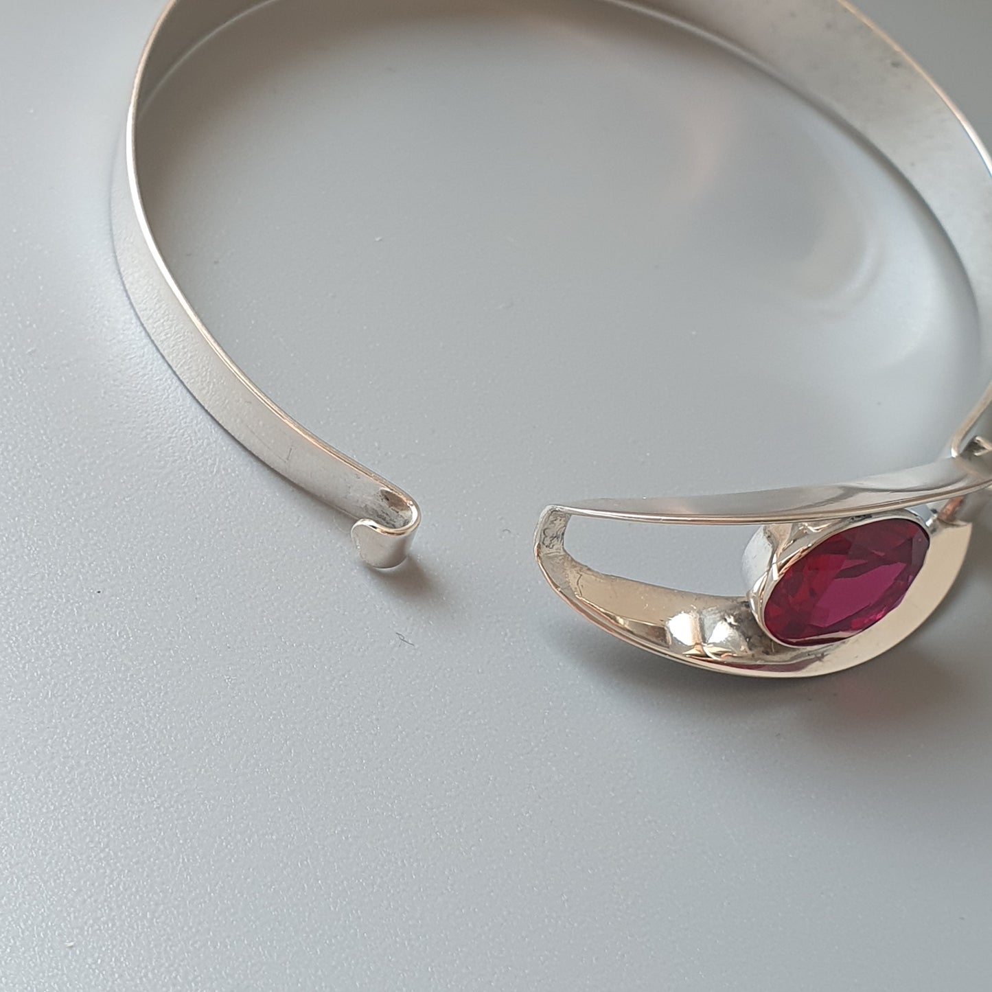 Silver bracelet with a pink gemstone accent.