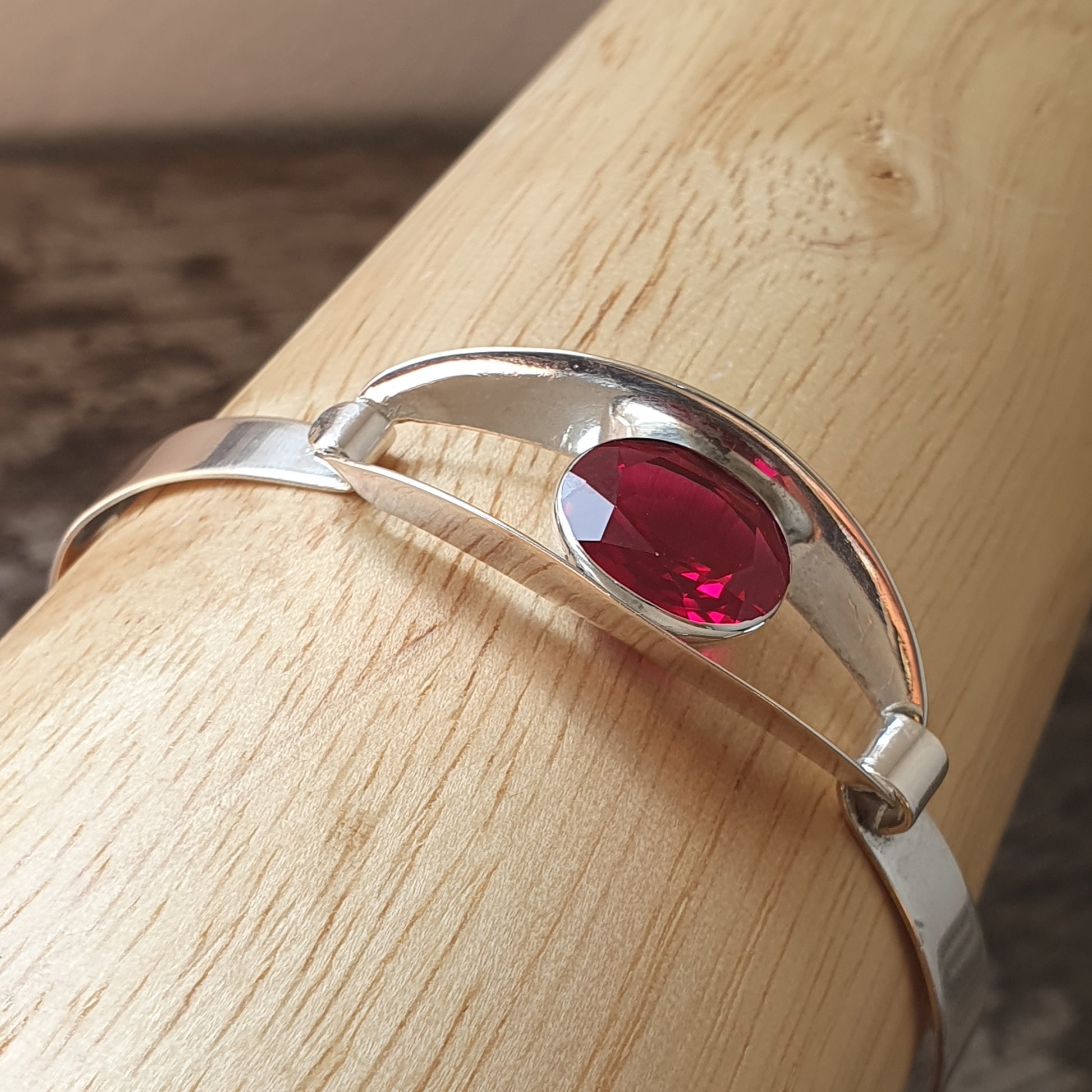 Silver ring with an oval red gemstone set in the center.