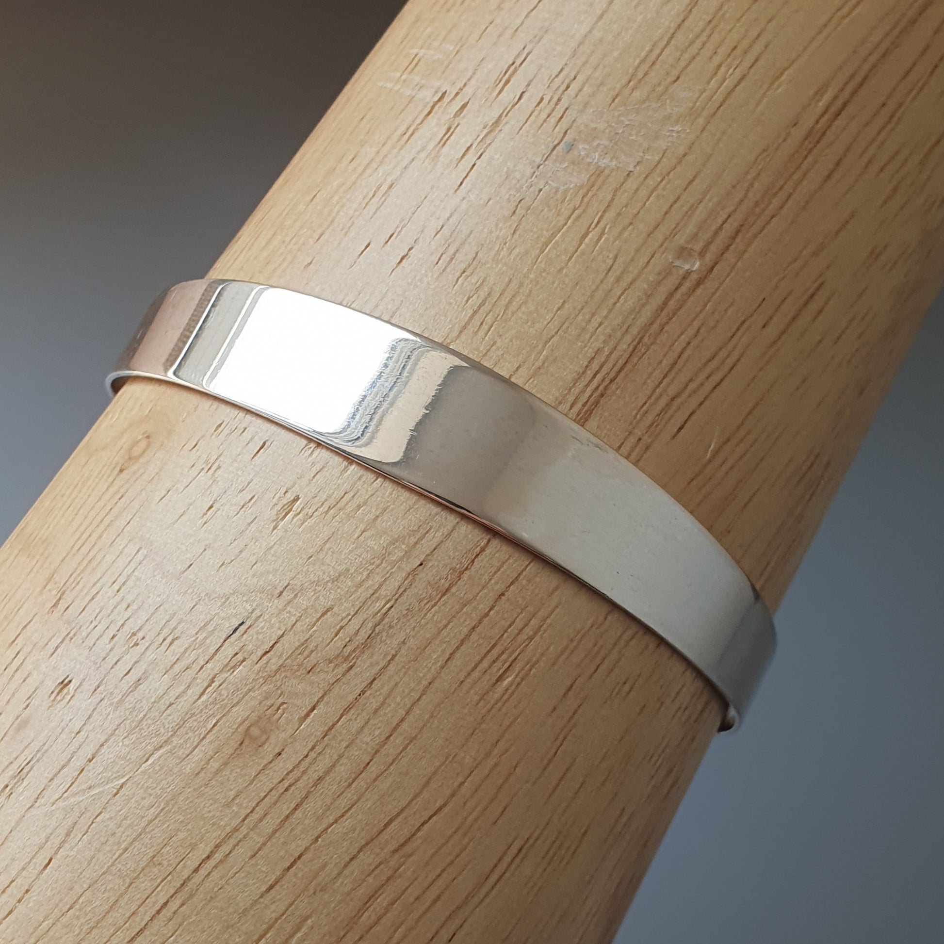 Silver metal ring or band wrapped around a wooden cylinder or post.