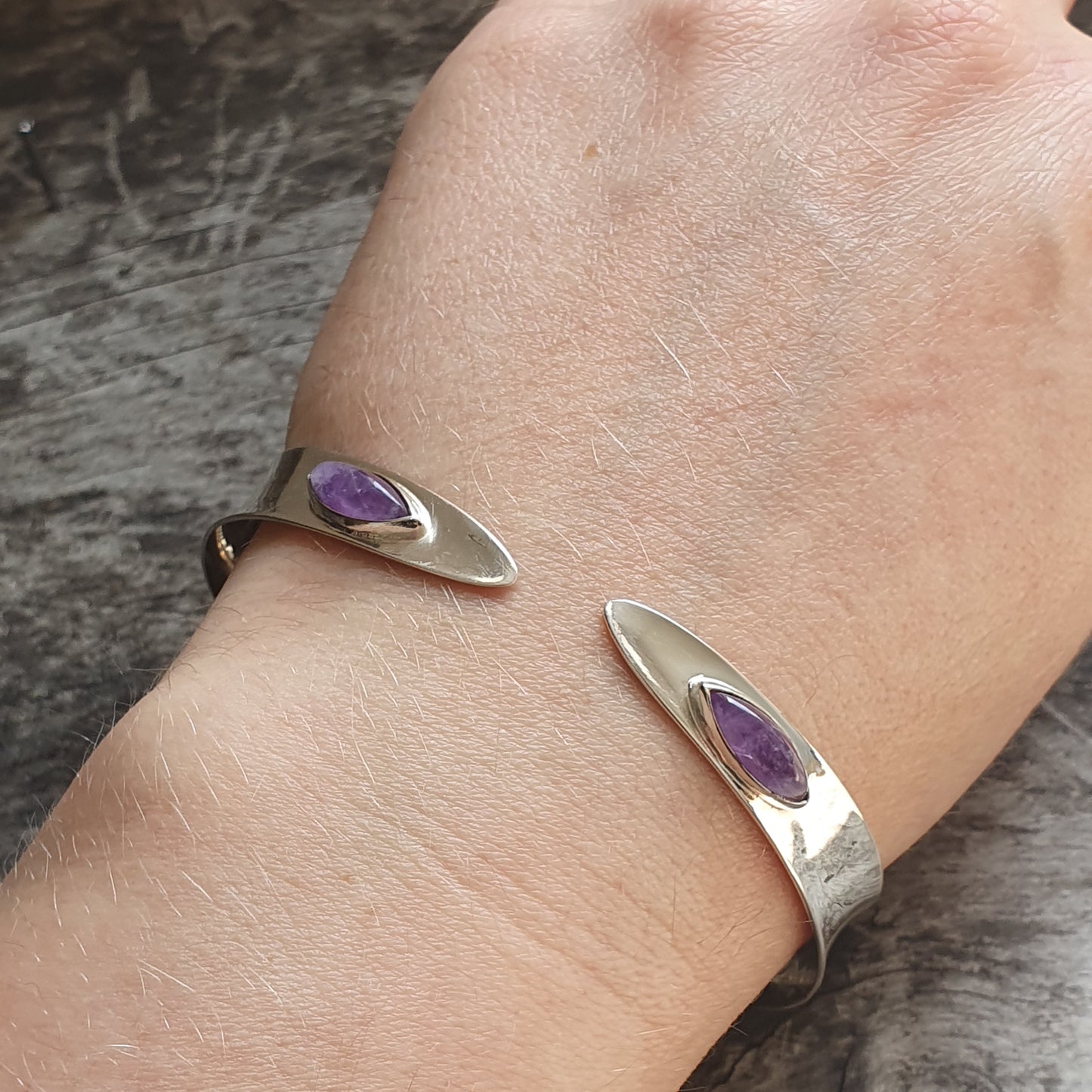 Silver cuff bracelet with two purple gemstone accents.