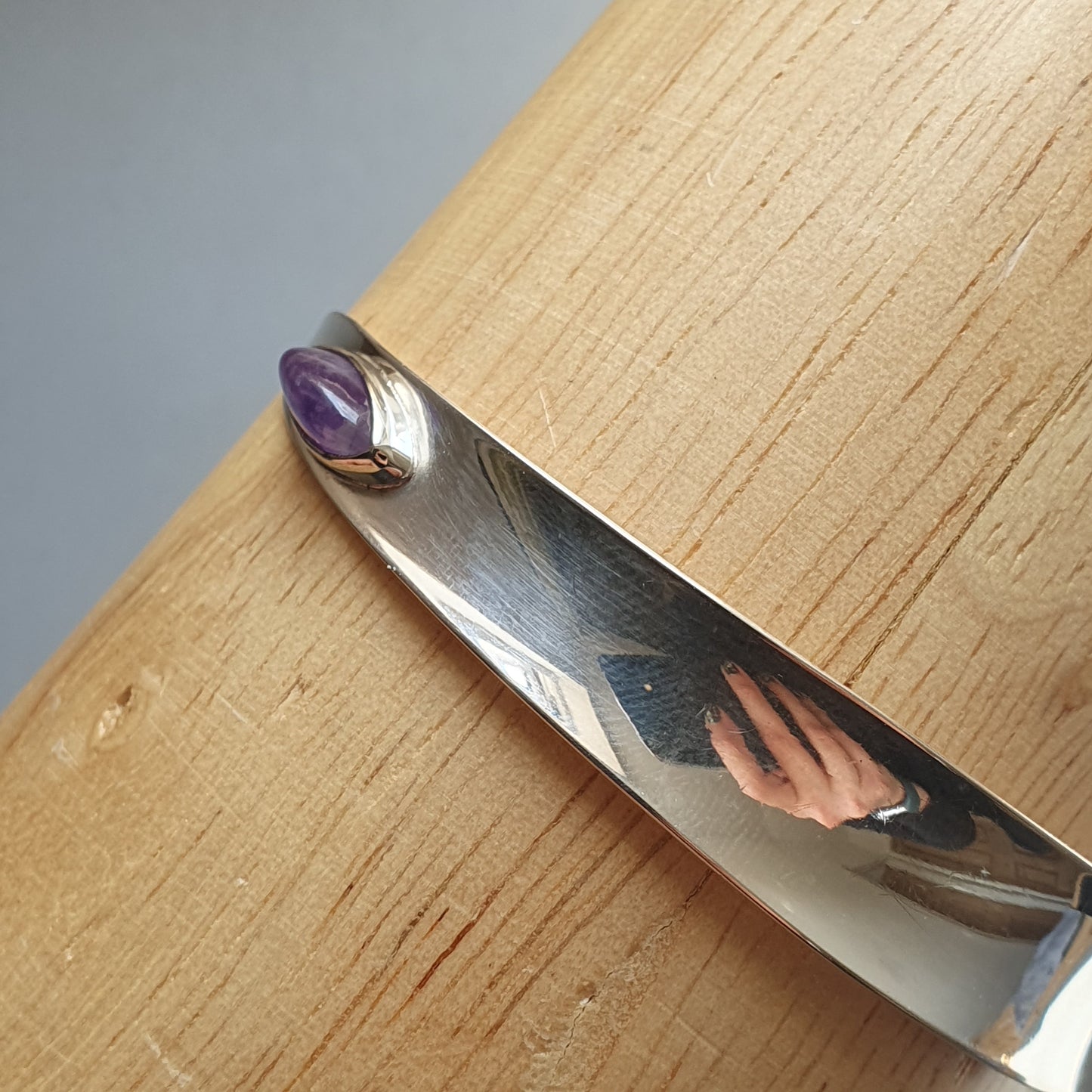 Silver bracelet or bangle with a purple gemstone accent.