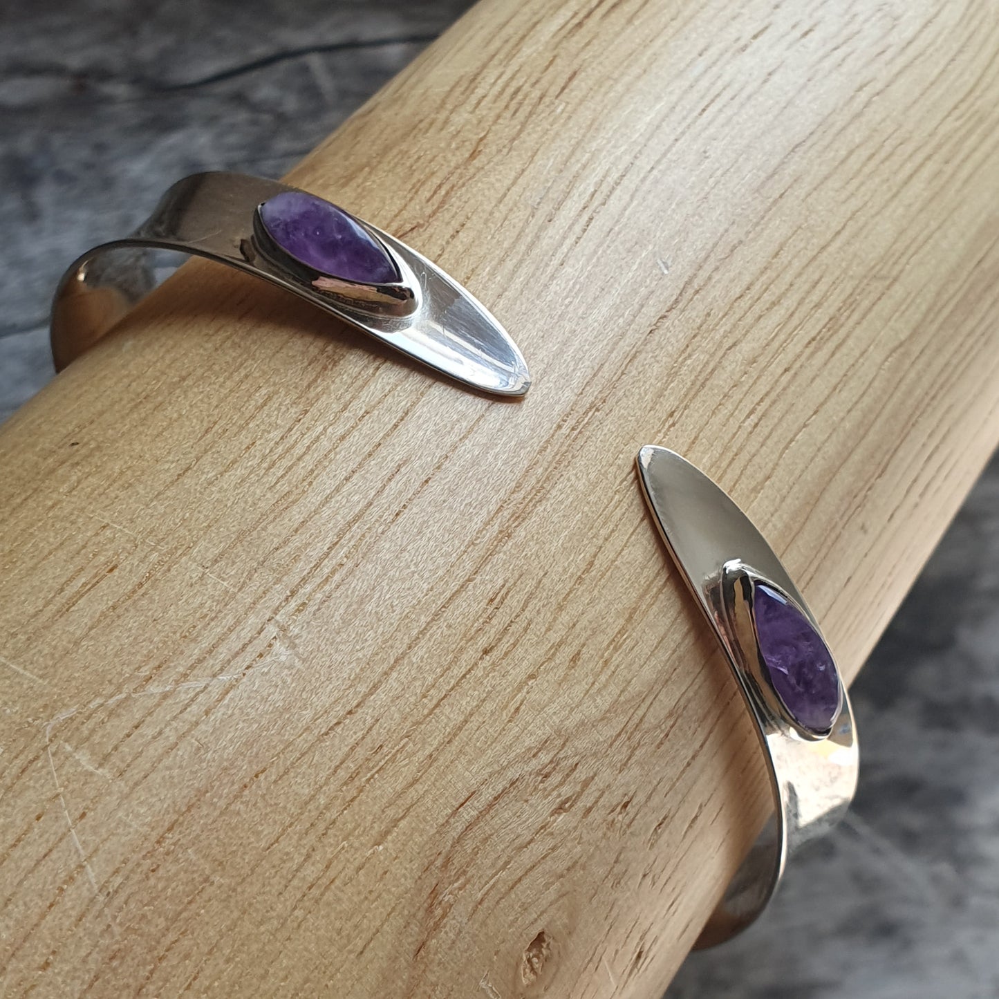 Silver bracelet with a purple gemstone inlay.