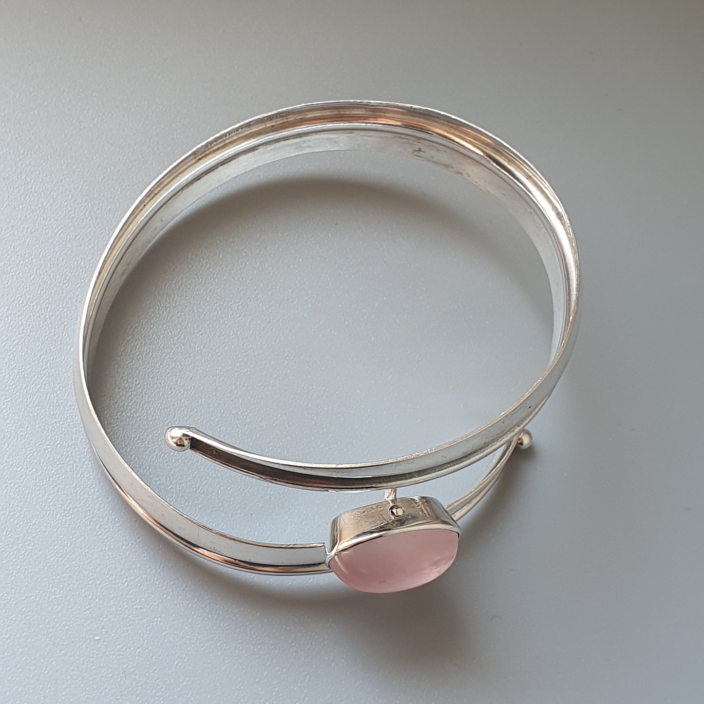 Silver bangle bracelet with a pink gemstone or cabochon accent.