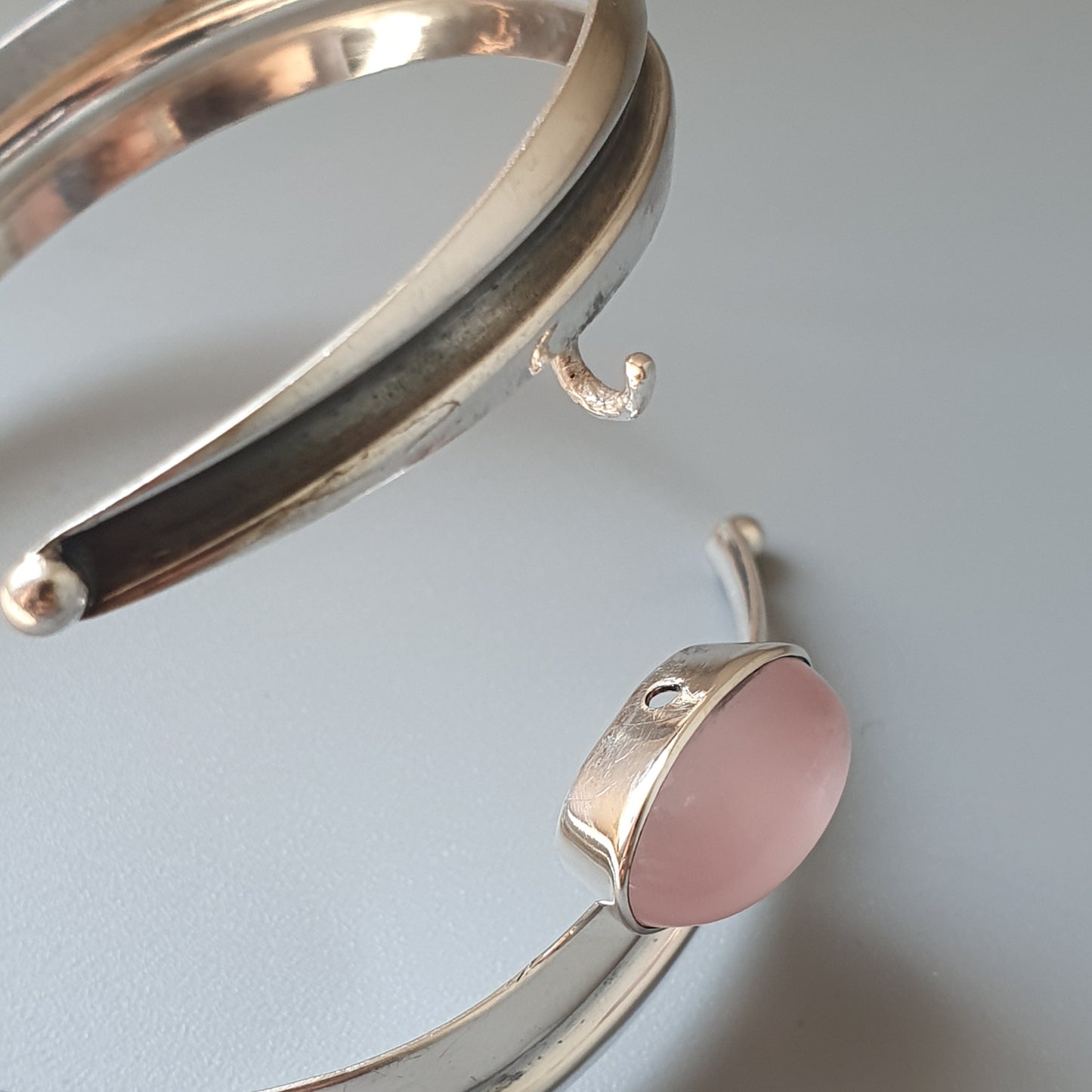 Silver bangle bracelet with a pink oval accent.