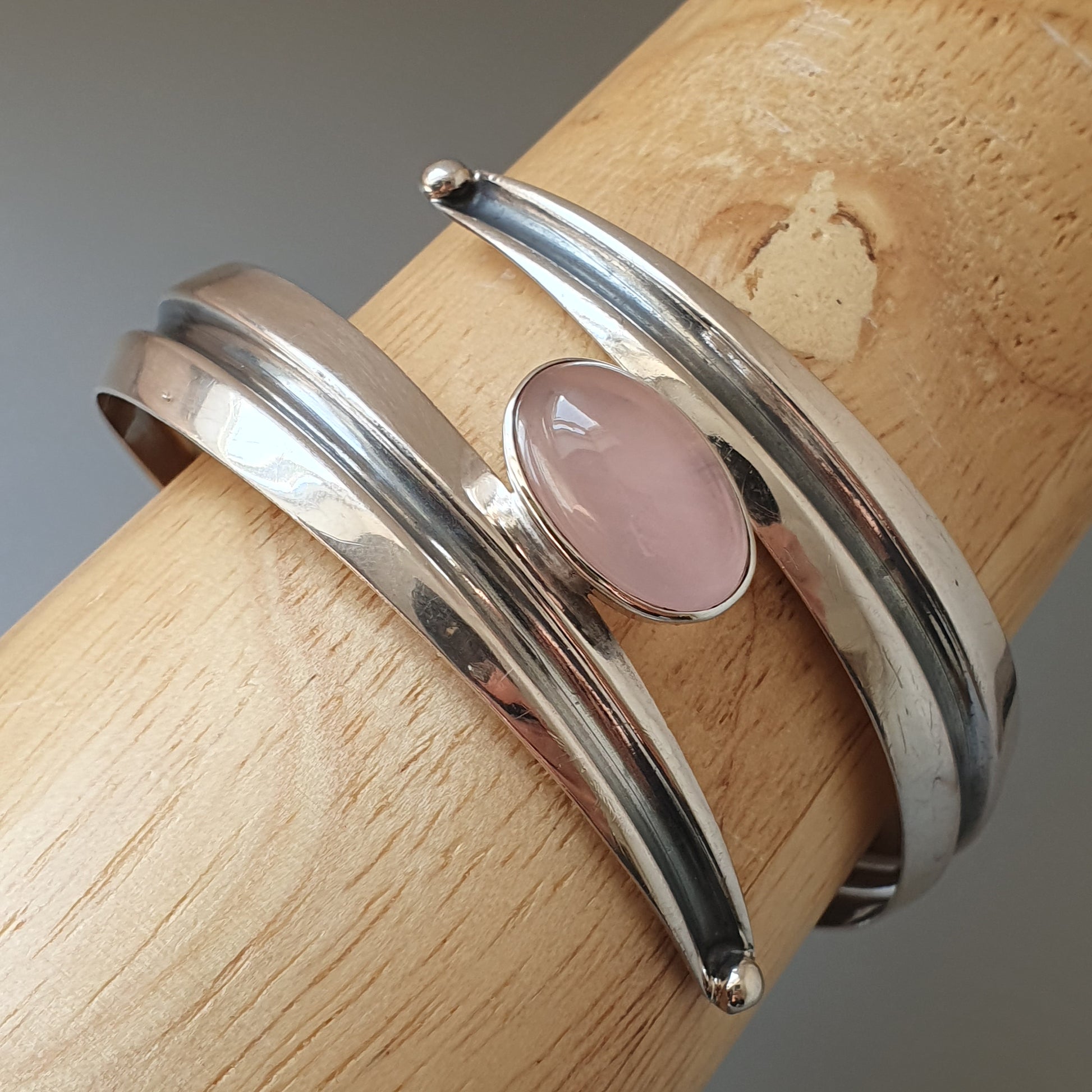 Silver bracelet with a pink oval gemstone.