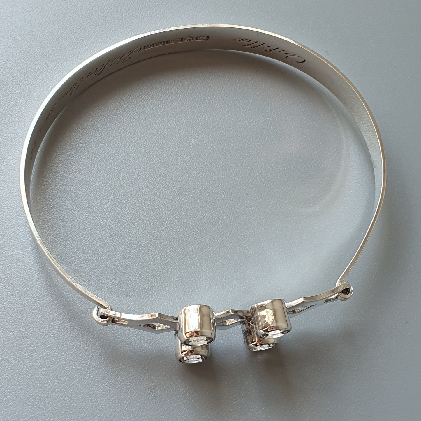 Silver bangle bracelet with two cylindrical charms or beads attached to the clasp.