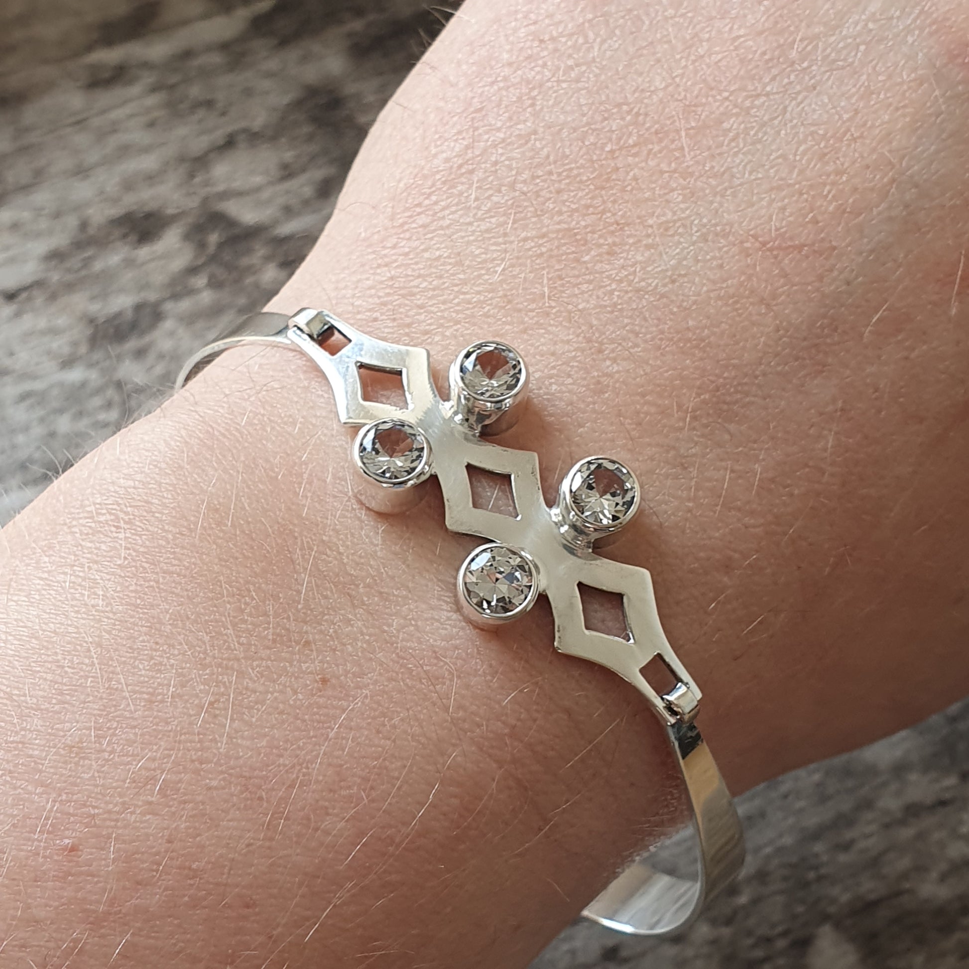 Silver bracelet with diamond-shaped elements and gemstones.