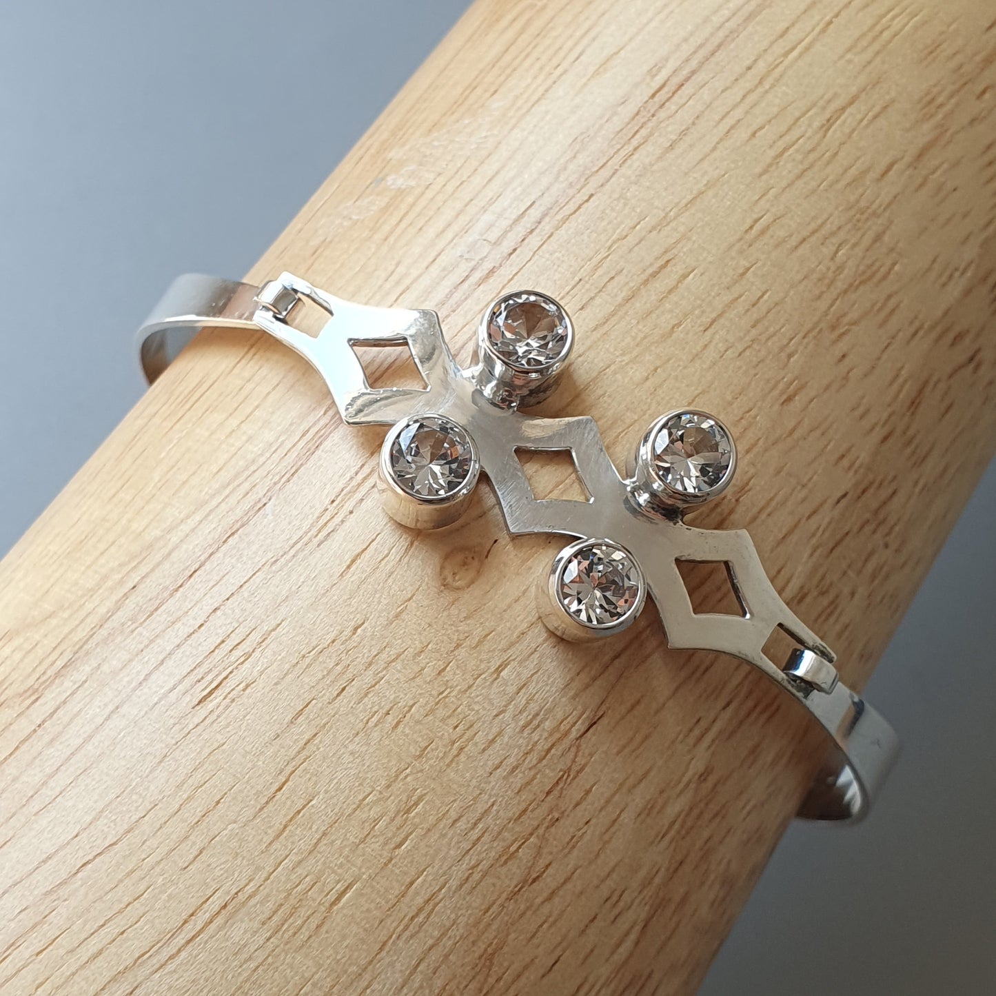 Delicate silver ring with a cross-shaped design featuring four small diamonds.