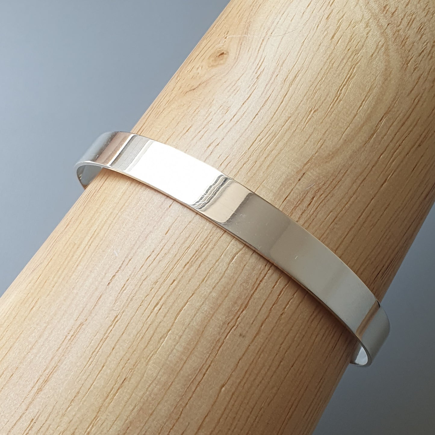 Silver metal band or ring wrapped around a wooden cylinder.