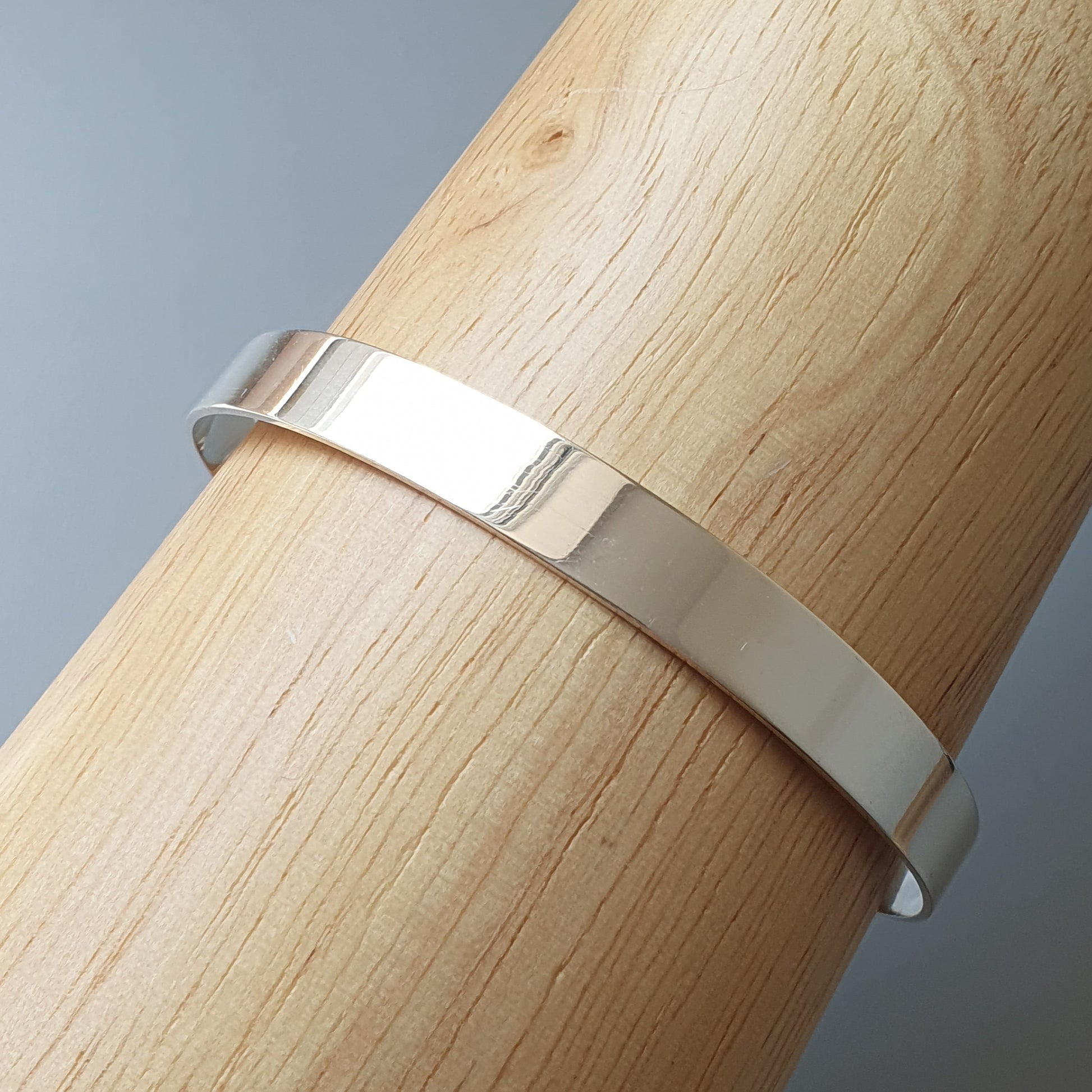 Silver metal band or ring wrapped around a wooden cylinder.