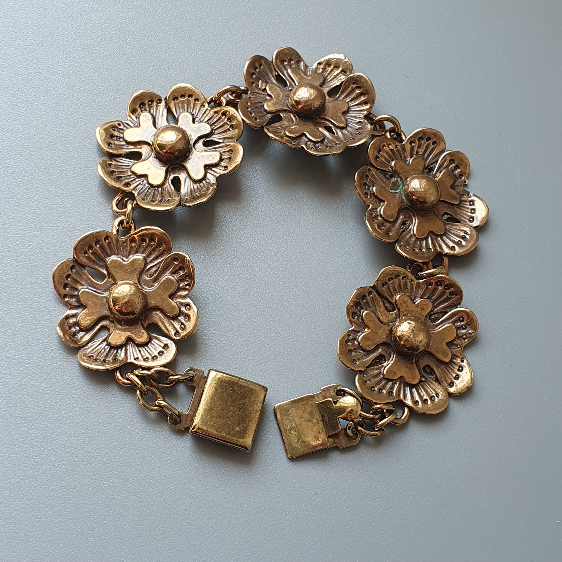 Gold-toned floral bracelet with five flower-shaped links and a clasp.