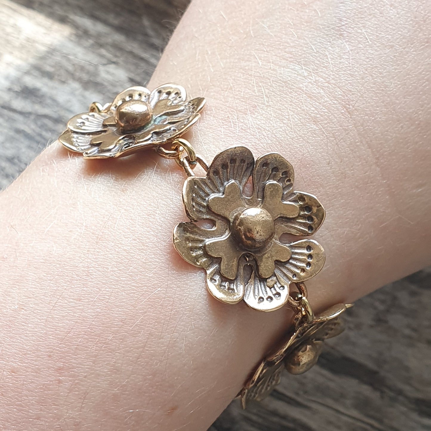 Gold-toned floral bracelet with three dimensional flower charms.