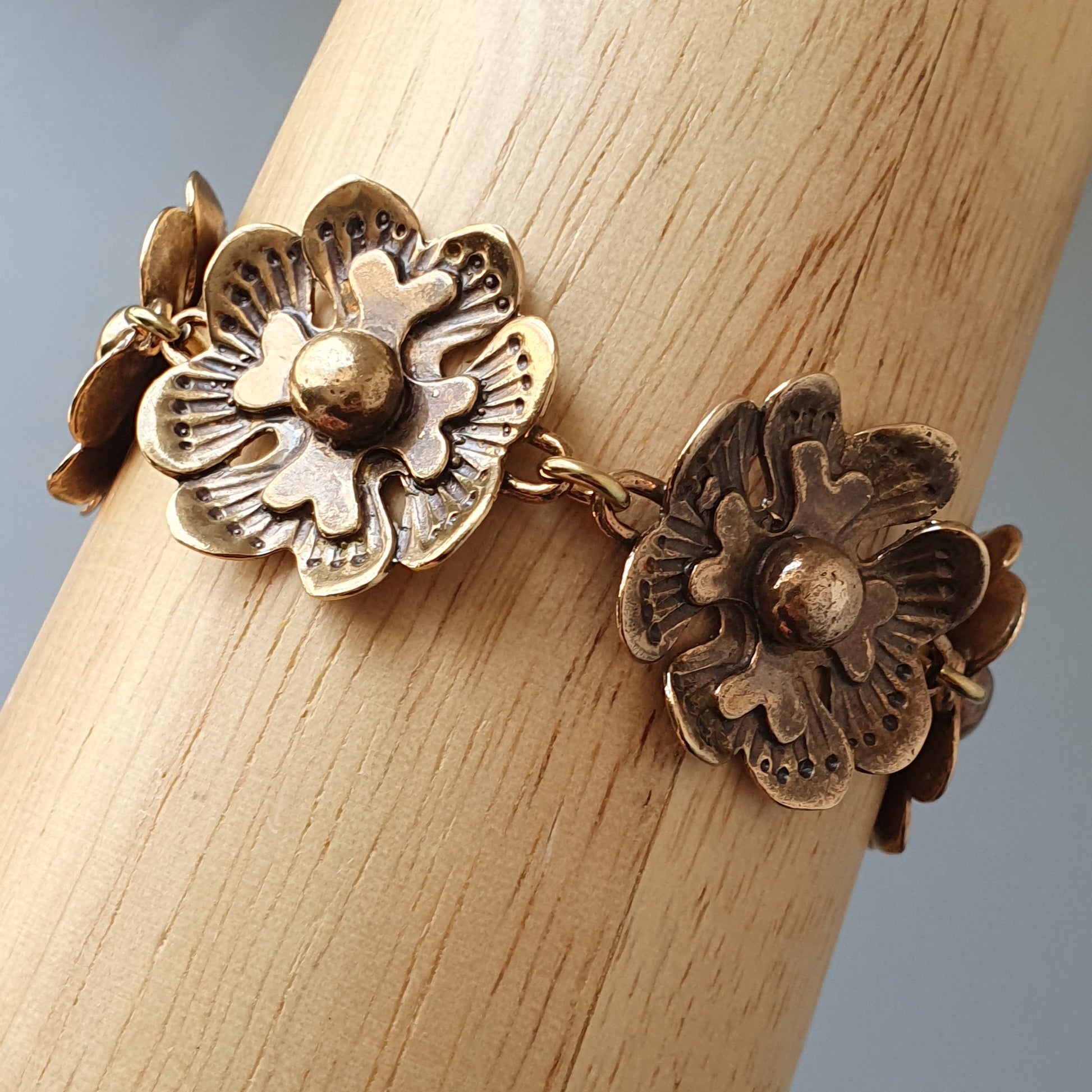 Antique-style floral bracelet with two intricate metal flower charms connected by a chain.