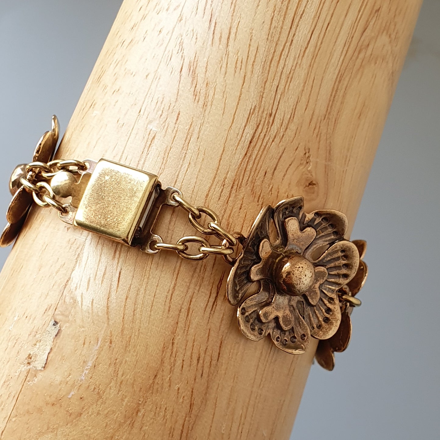 Antique-style bracelet with a floral charm and gold-toned chain links.