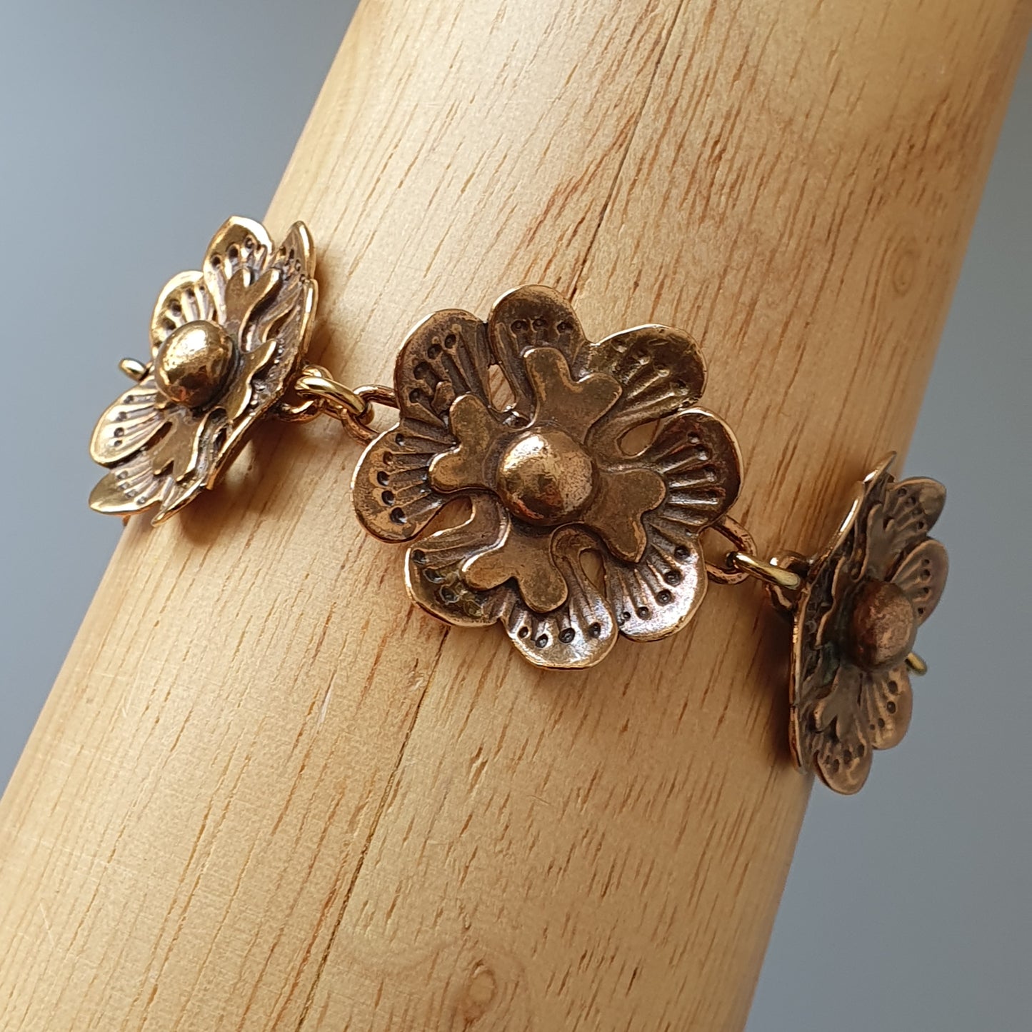 Gold-toned floral bracelet with three interconnected flower-shaped charms.