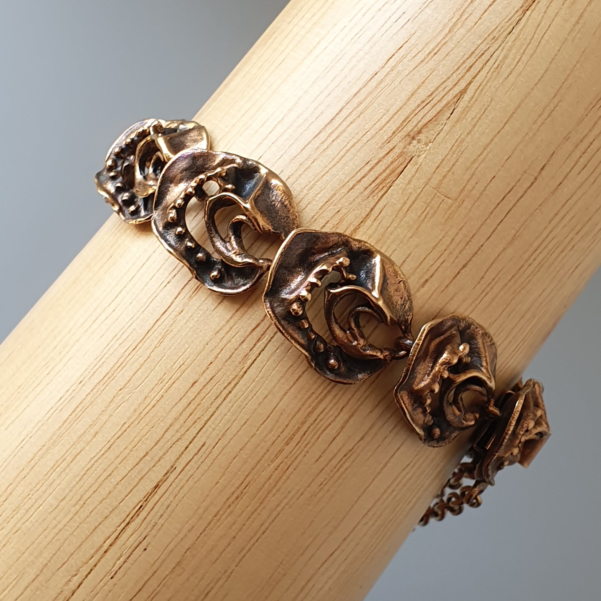 Bronze-colored bracelet with decorative crescent moon shapes linked together.