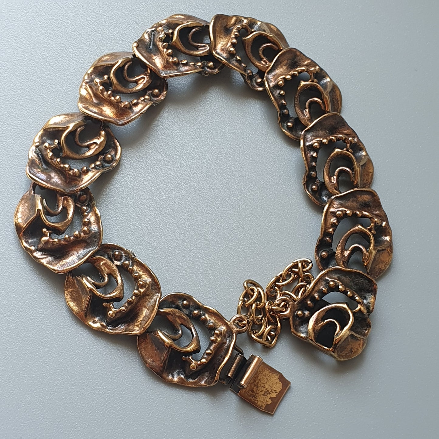 Bronze or copper-toned bracelet with decorative crescent moon shapes linked together.