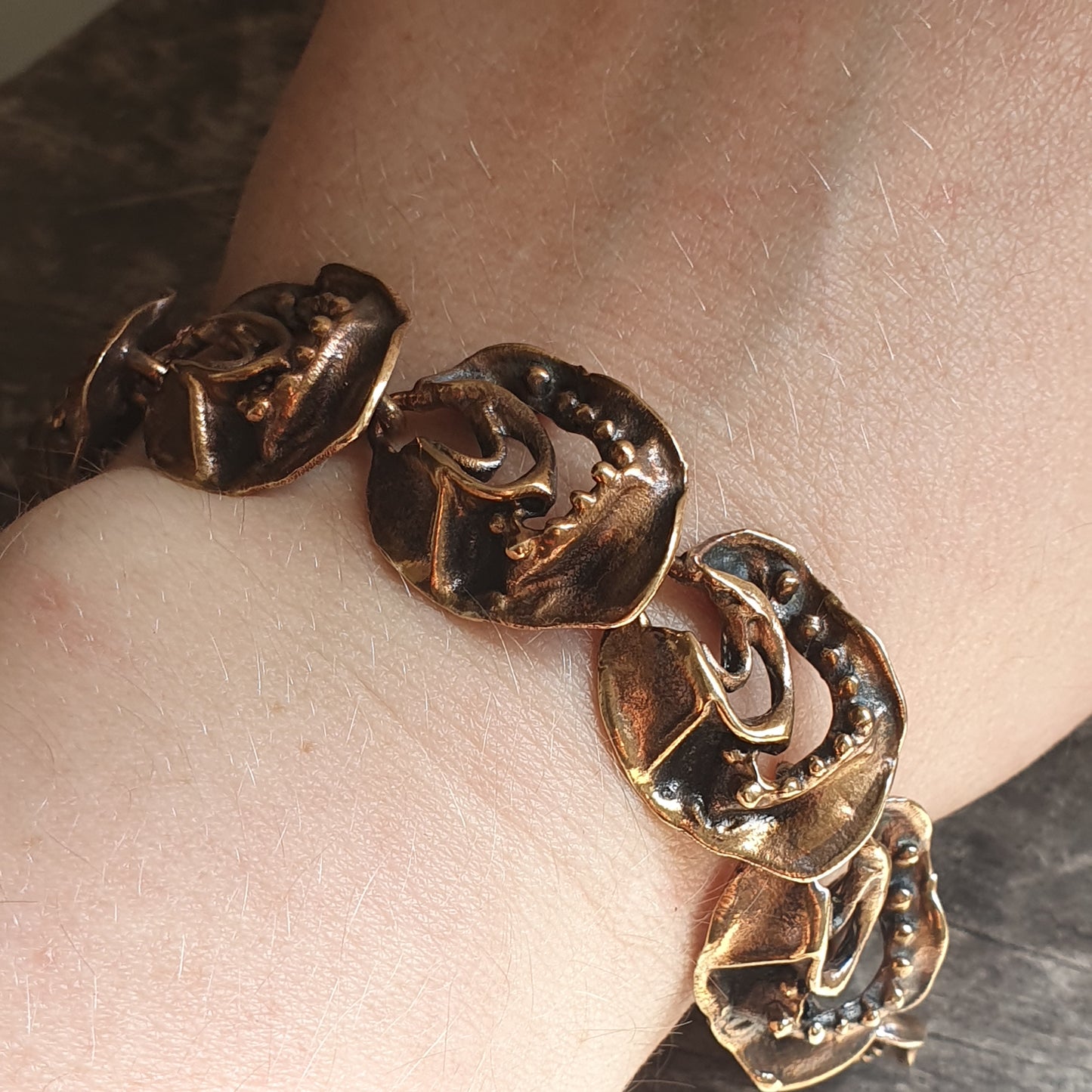 Gold-toned bracelet with irregular shaped links featuring decorative patterns.