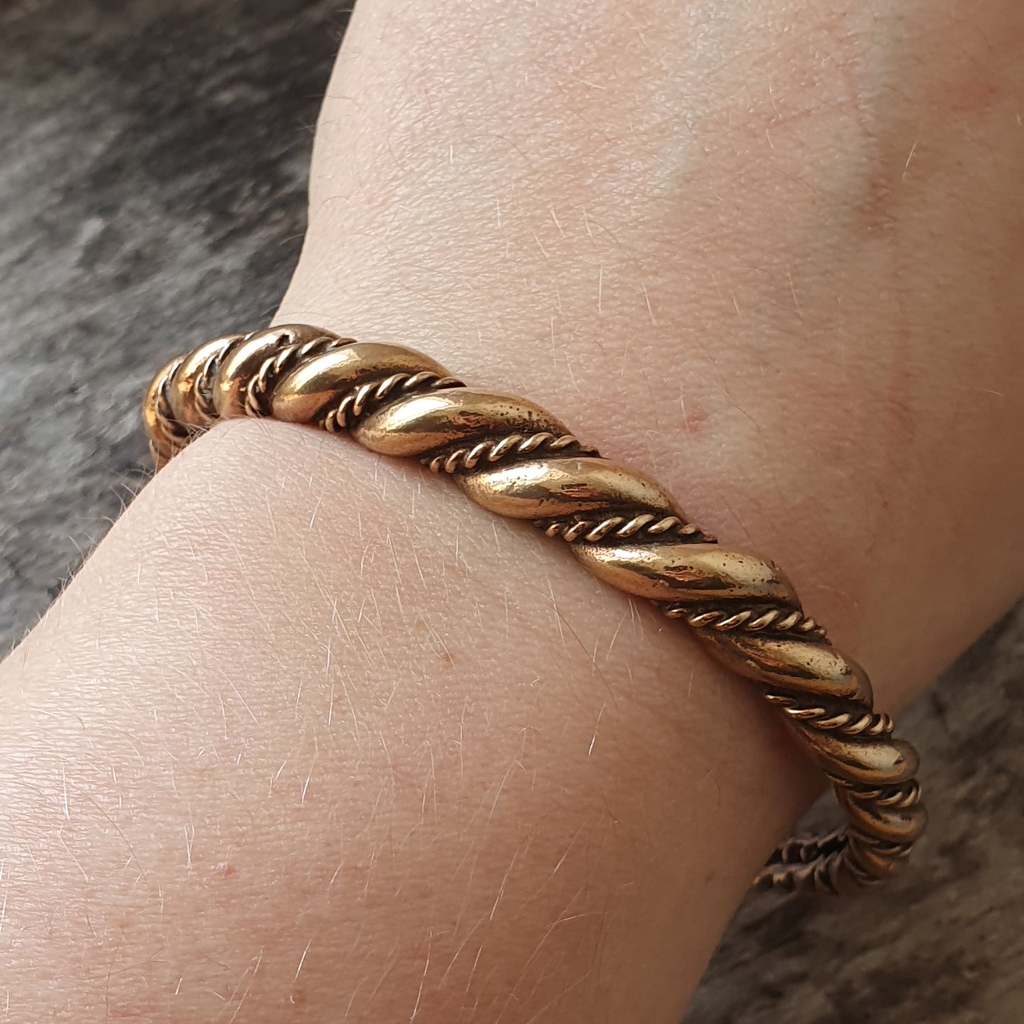 Gold twisted rope bracelet worn on a wrist.